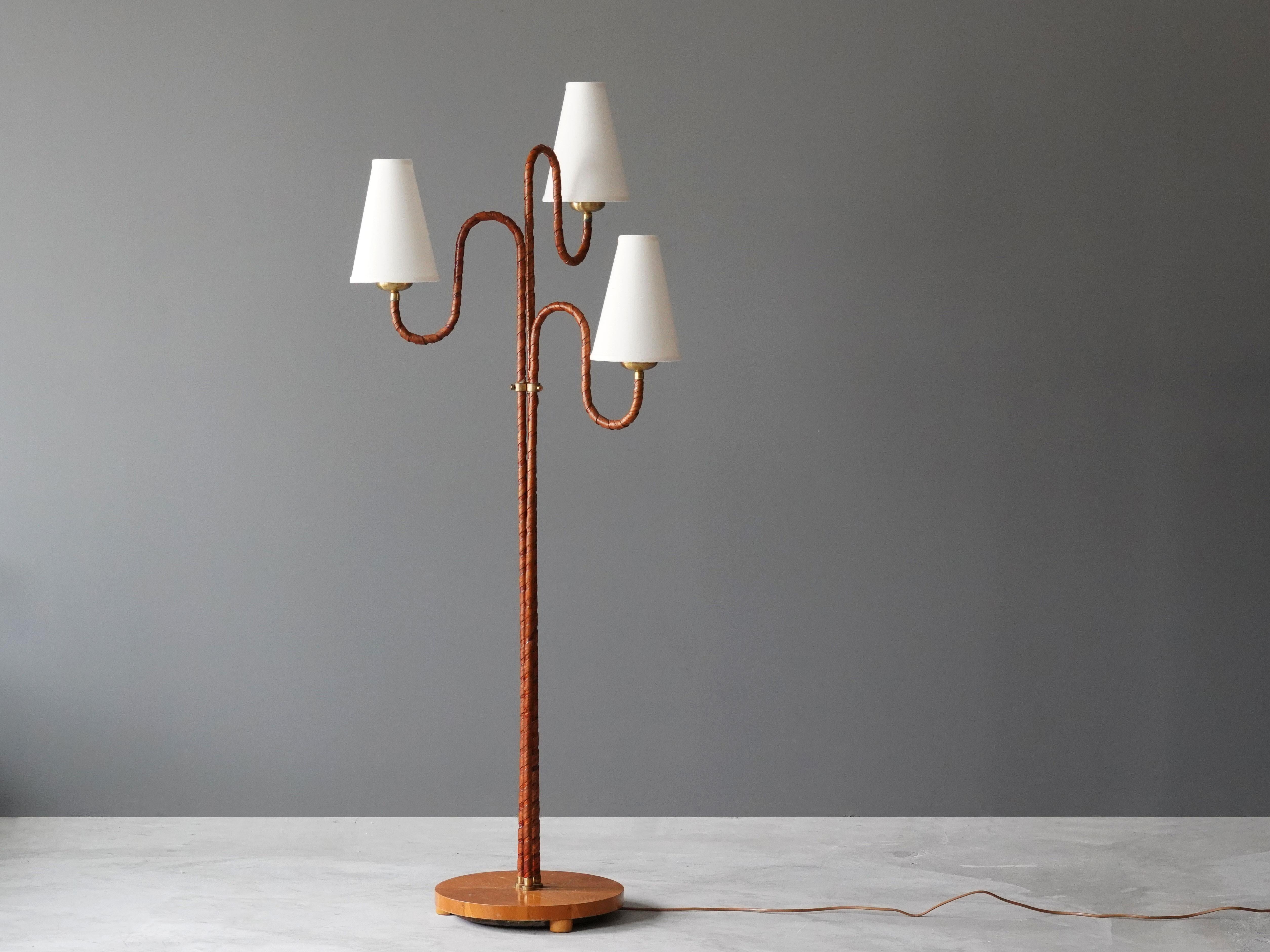 An organic three-armed floor lamp. Designed by an unknown Swedish modernist designer, 1930s. Possibly manufactured by Böhlmarks. Produced in rattan, wood, linen, and brass. Arms adjustable. 

Other designers working in the organic style include Jean
