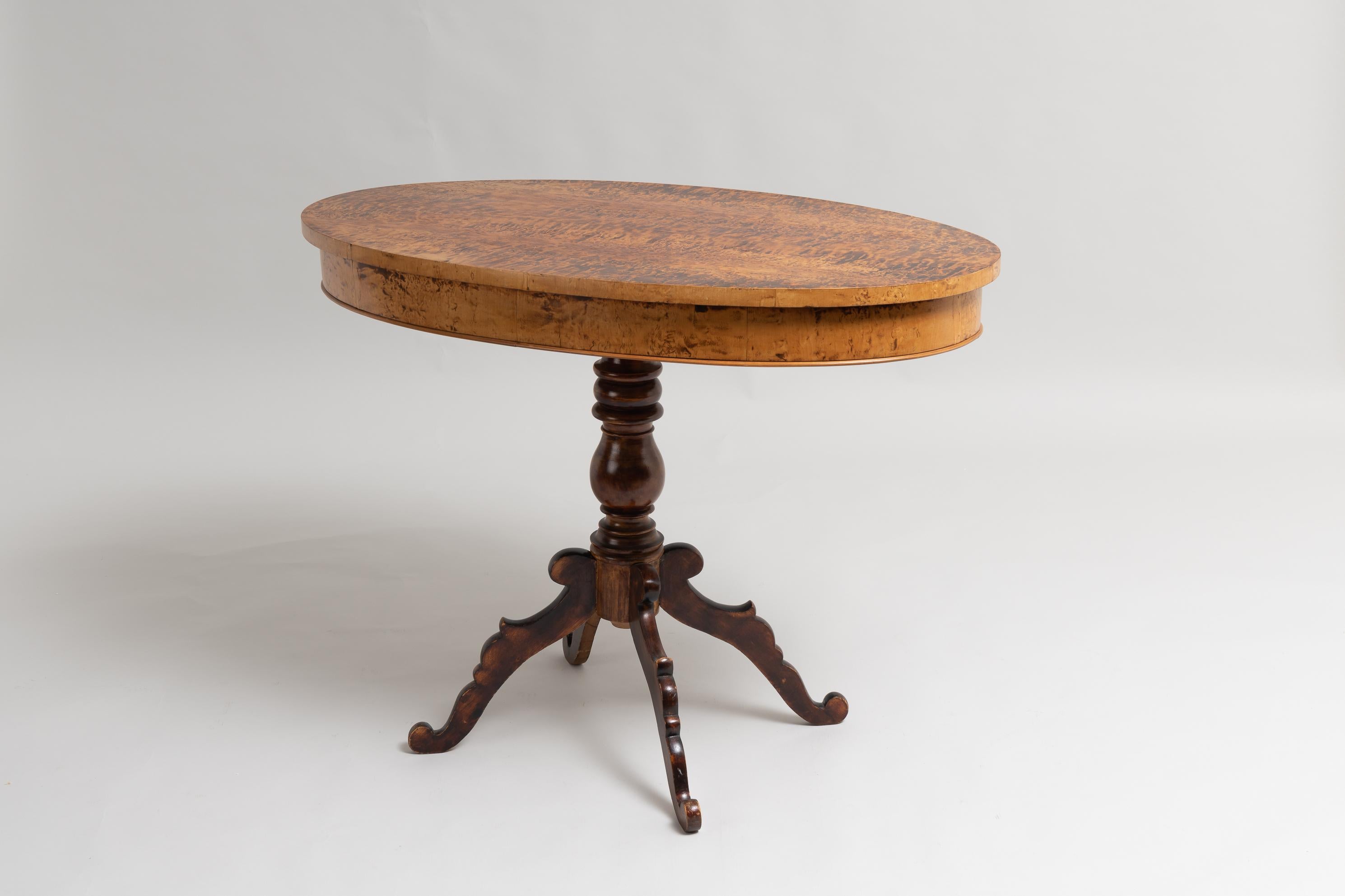 Table centrale de style néo-rococo, fabriquée en Suède entre 1860 et 1870. La table a une base à colonne unique avec 4 pieds et un dessus de table ovale. Le plateau de la table est plaqué de racines de bouleau et la surface a été traitée pour que le