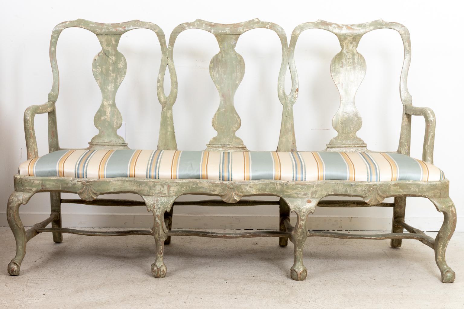 Gustavian style Swedish painted three seat bench with pierced, vase shaped back splat and upholstered seats. The bench also features a bottom stretcher and ball-and-claw feet. Please note of wear consistent with age including distressed finish to