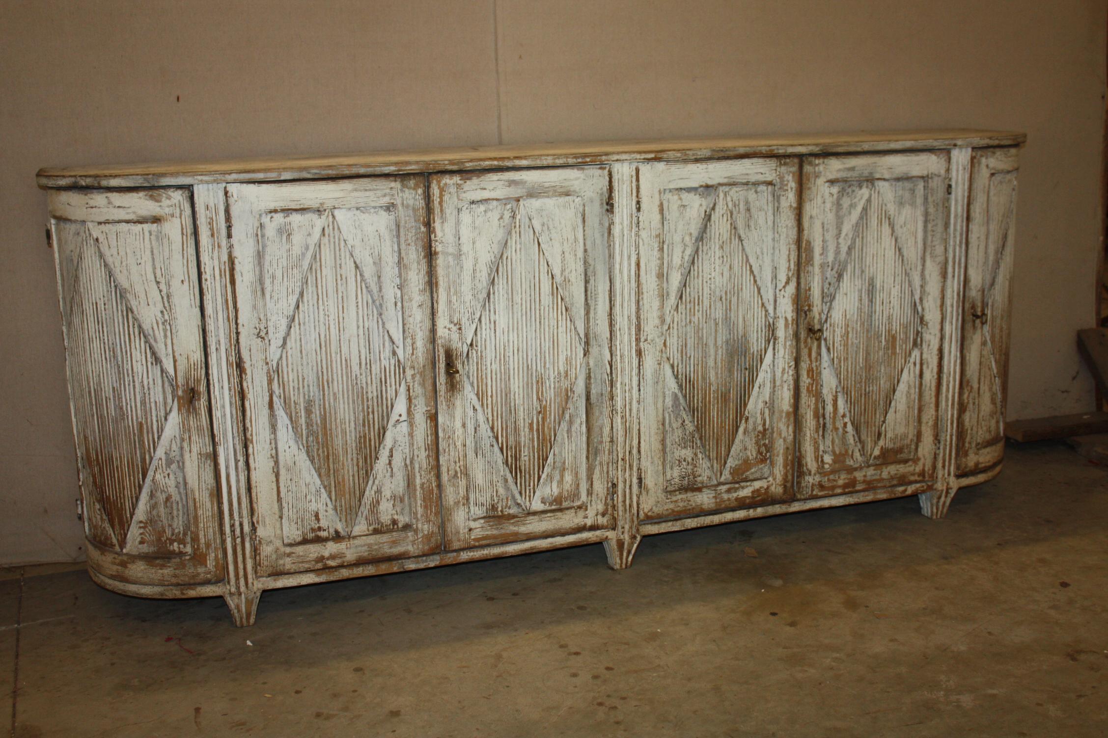 Swedish enfilade or sideboard in a simple design and good scale, hand dry scraped to show traces of chalky white and pale blue paint. This Swedish enfilade or sideboard has a very elegant curved form to the side, four doors to the front and two