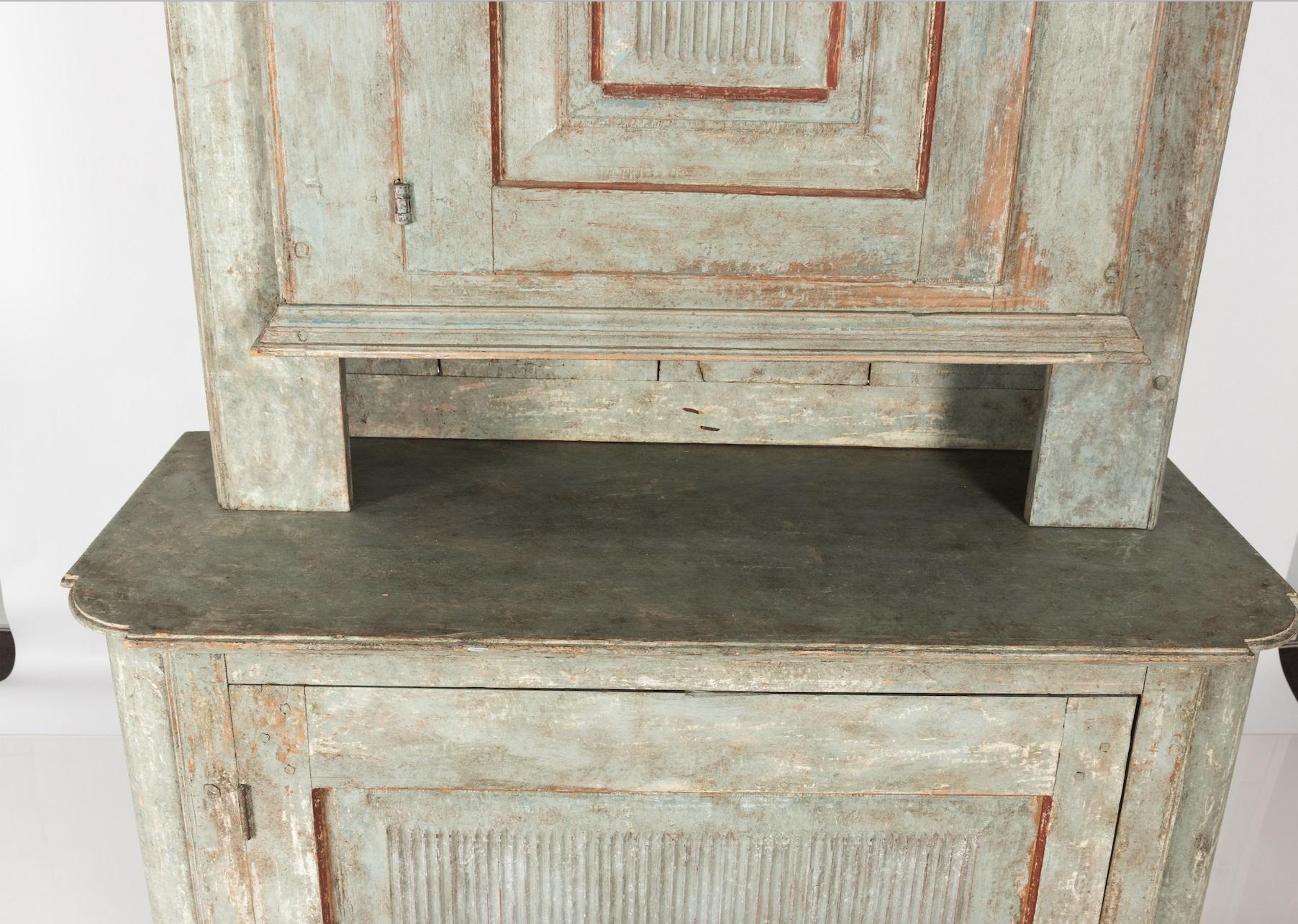 Handsome antique Gustavian style cabinet made in Sweden circa late 19th century. This rustic piece features contrasting seafoam green and red historic paint. Lovely patina with rich texture throughout the surface. Decorative pediment cornice marks