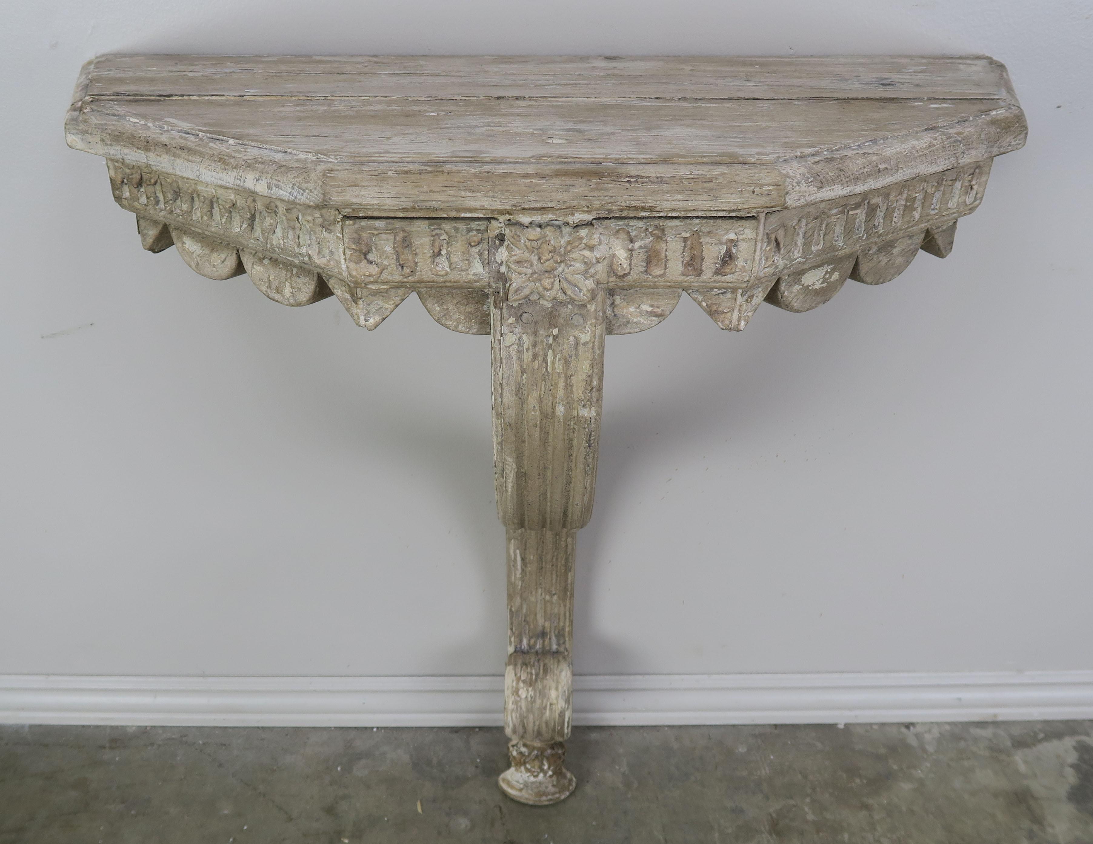 Swedish painted carved wood console table beautiful scalloped apron and single fluted legs with scrolled bottom. The console has a weathered finish throughout.