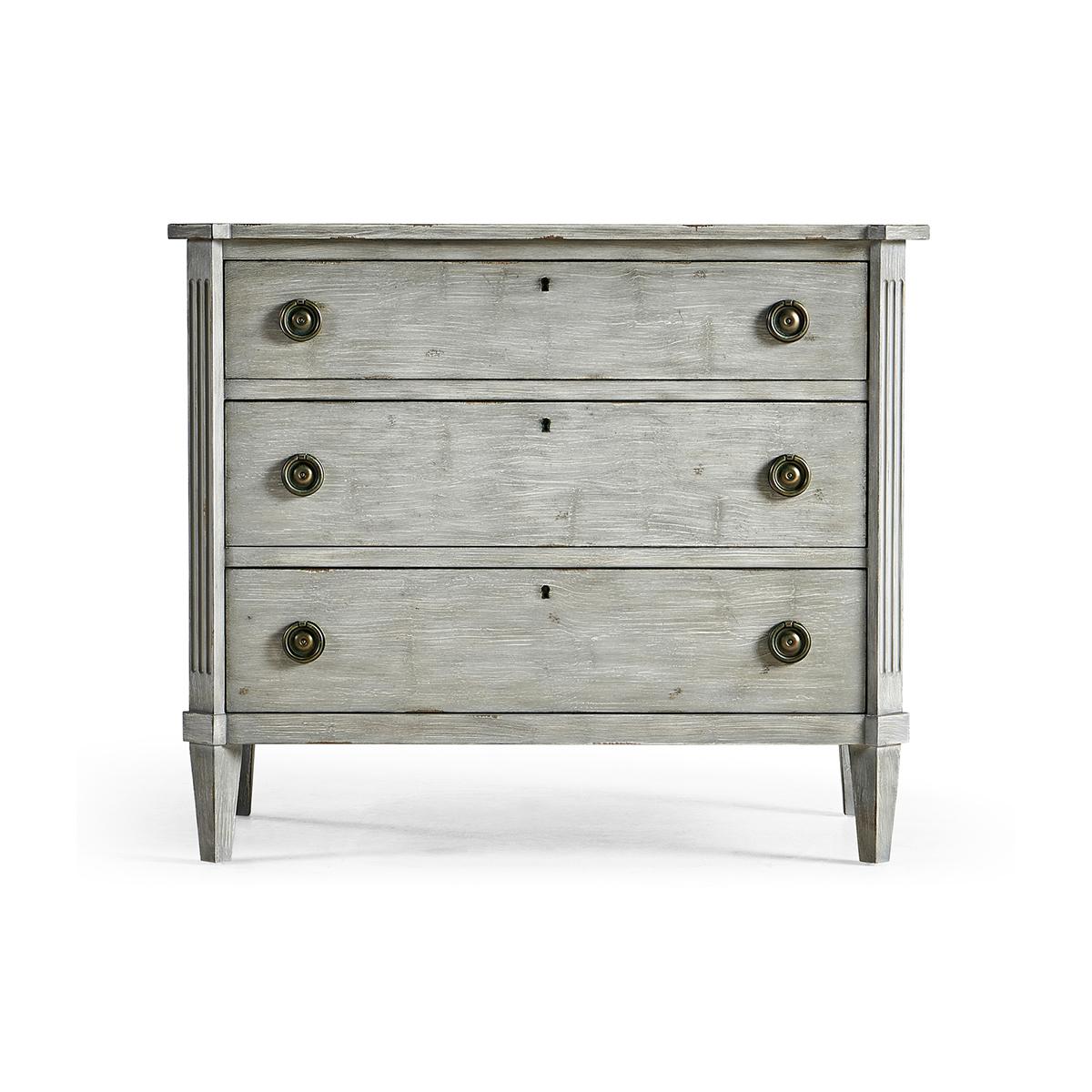 Swedish painted commode, this neo-classic painted commode in an antiqued grey finish with three long lockable drawers, canted corners with fluted stiles, and brass ring pull handles on square tapered legs. 

Dimensions: 38