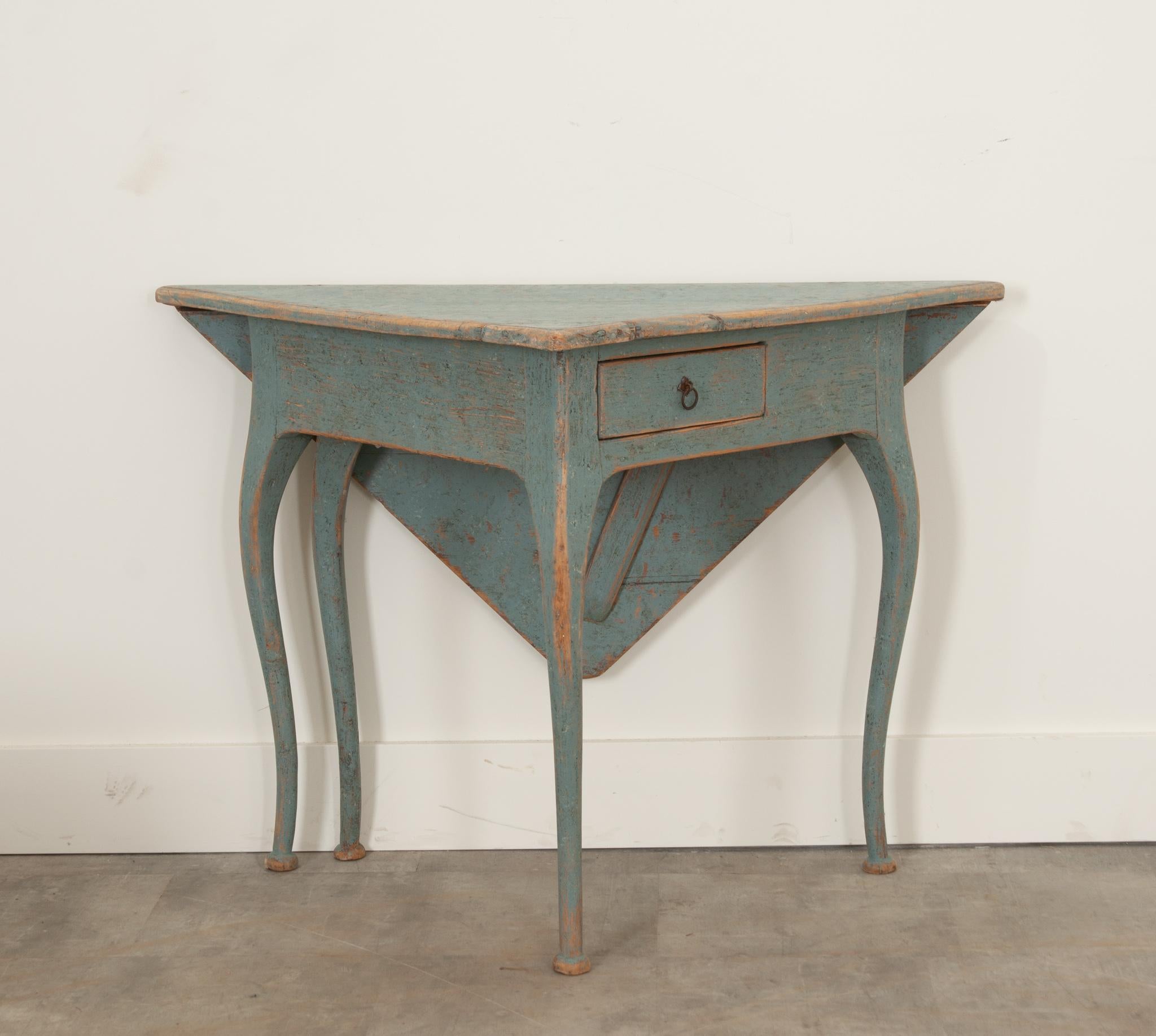 A darling 19th century Swedish corner or handkerchief table of petite proportions with a wonderfully worn sky blue painted finish. The triangular top is fixed with a rear-drop leaf that swings up to form a square surface, being supported by a