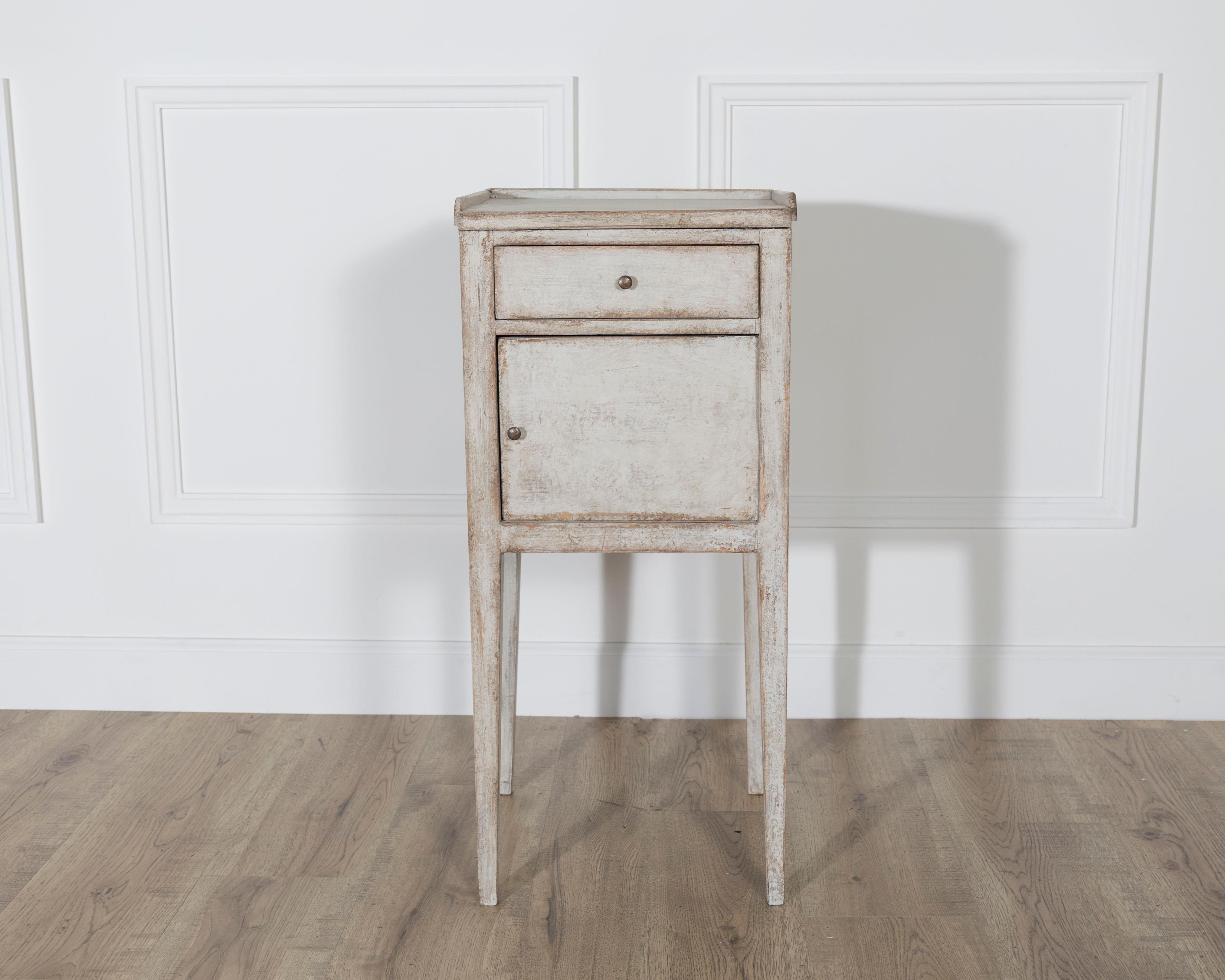 Une table de nuit suédoise peinte de la seconde moitié du 19e siècle, exsudant le charme rustique et la simplicité scandinave. Fabriquée en pin, cette pièce présente un plateau rectangulaire au-dessus d'un seul tiroir étroit équipé d'une petite
