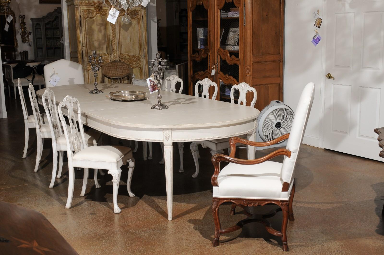 A Swedish Gustavian style painted wood extension dining room table from the 19th century, with four new leaves, carved rosettes, beading and fluted accents. Created in Sweden during the 19th century, this Swedish dining room table features an oval