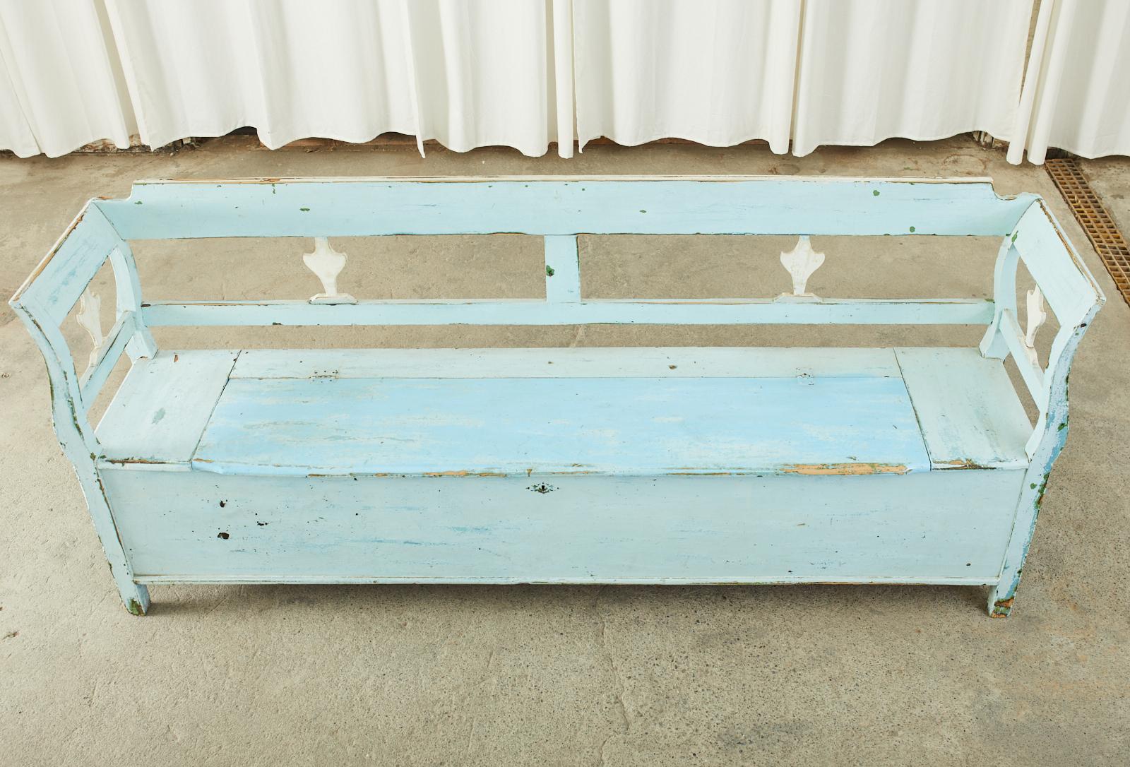 19th century rustic country Swedish farmhouse hall bench or settle with large storage bin. The long bench is crafted from pine featuring a robin's egg blue painted finish. The finish has a beautifully aged patina full of character and charm with old