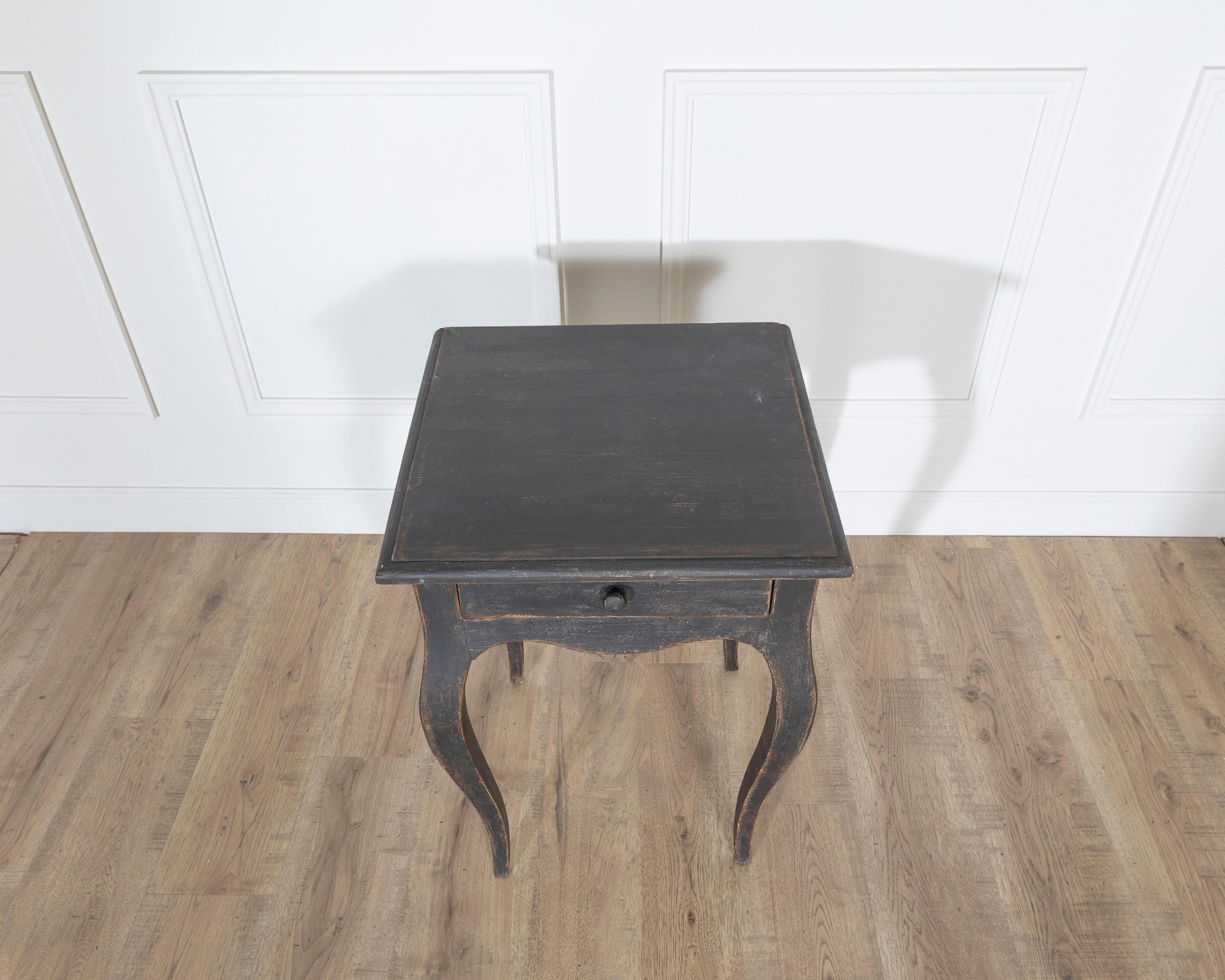 A graceful Swedish side table from circa 1840, embodying the light, lyrical lines of Scandinavian design from the mid-19th century. Crafted in solid pine and painted in a rich, timeworn black, the table’s surface has acquired a beautifully