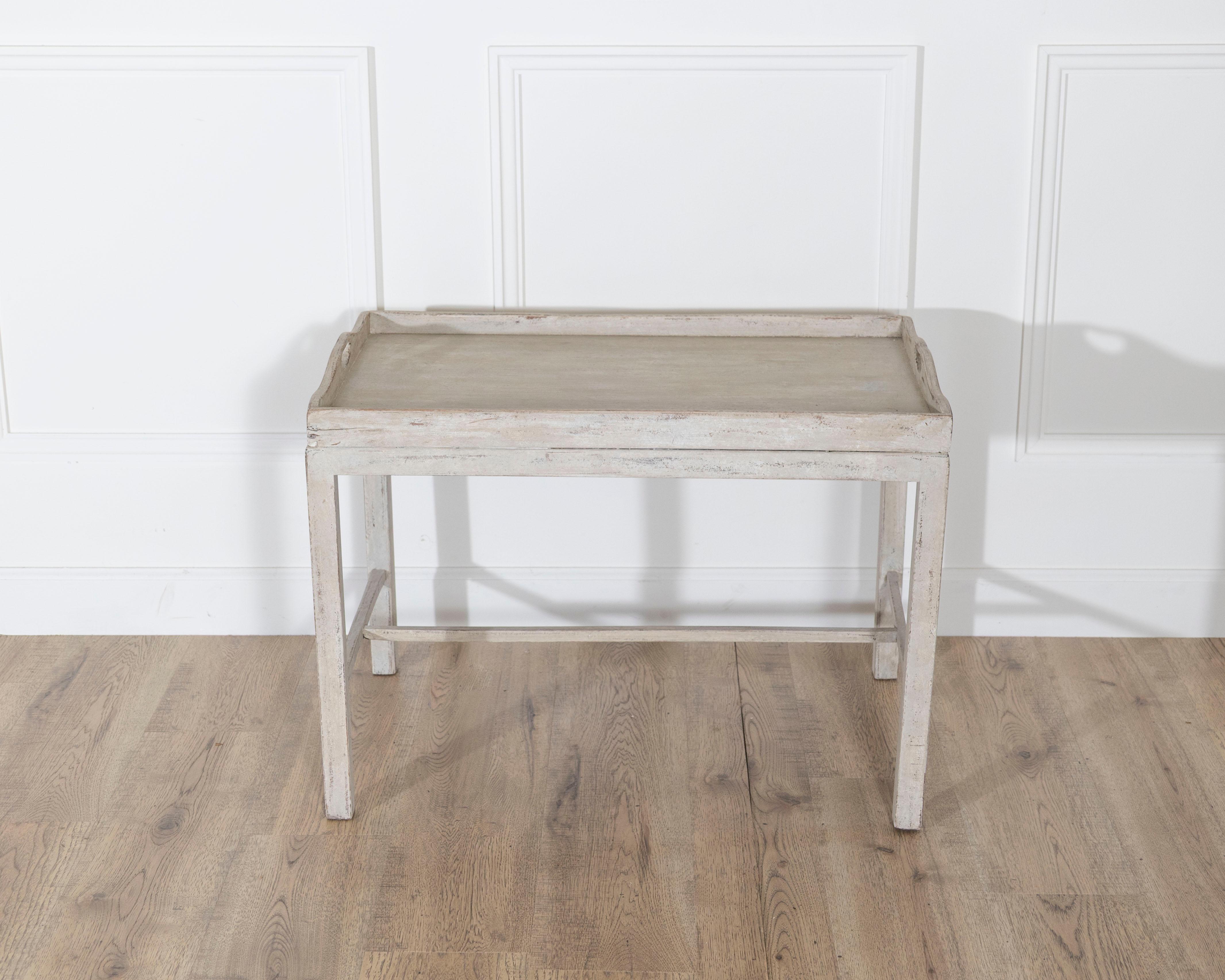 This charming Swedish tray table, dating to circa 1920, combines practical functionality with understated Scandinavian elegance. Crafted with clean, simple lines, the table features a raised tray-style top with subtly curved edges, ideal for serving