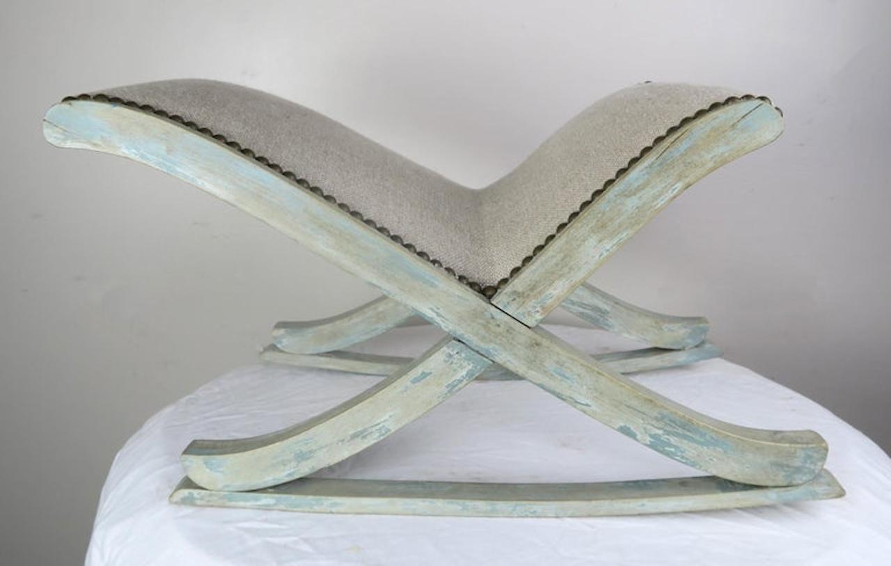 Swedish painted rocking stool that is newly upholstered in washed Belgium linen and finished with antique brass nailhead trim detail.