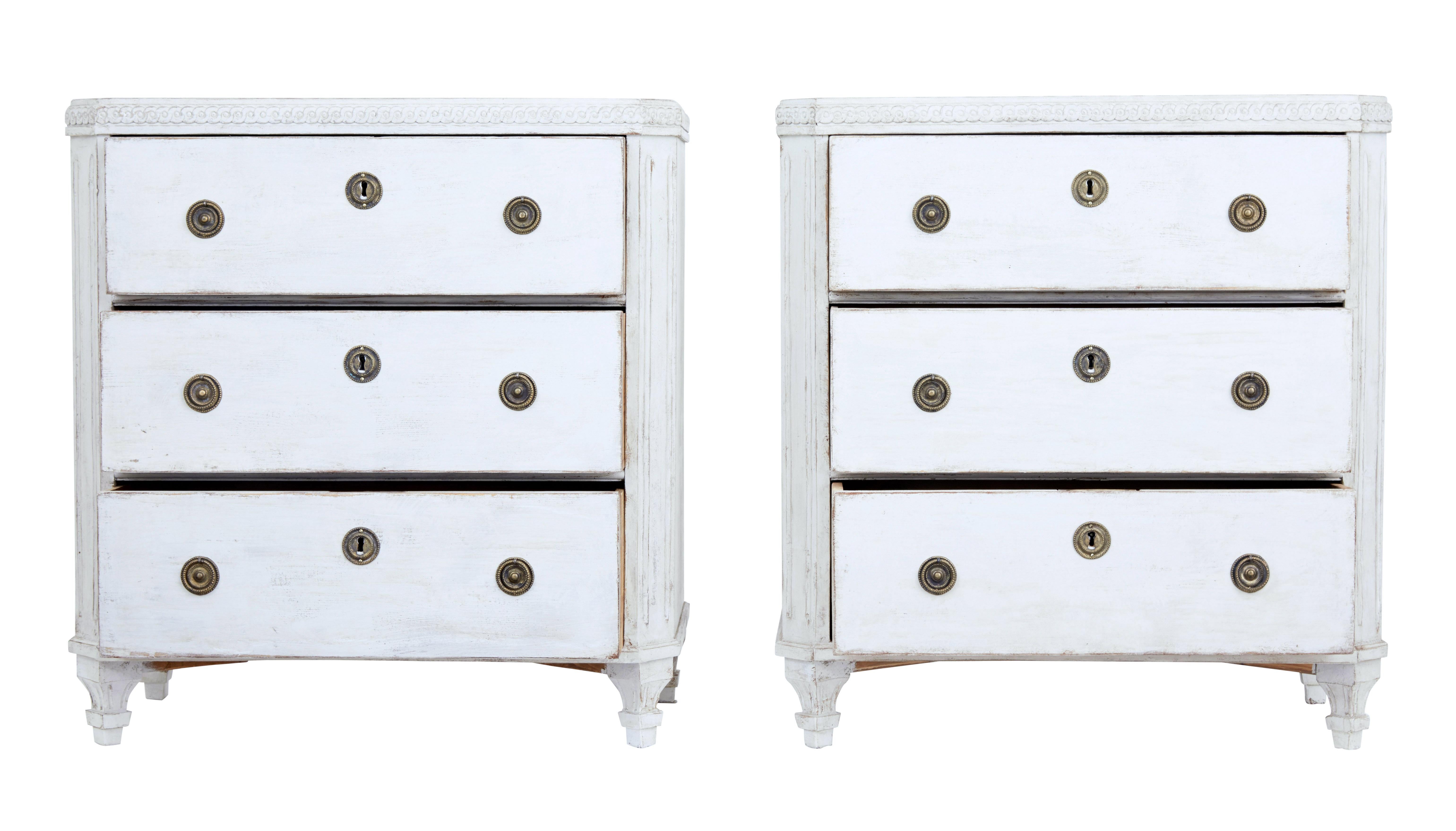 Pair of painted Swedish commodes, circa 1880.

Carved scrolling detail the top surface. Canted corners with fluted detail. 3 drawers with brass ring handles and escutcheons.

Standing on detailed tapered legs.

Later paint and hardware,