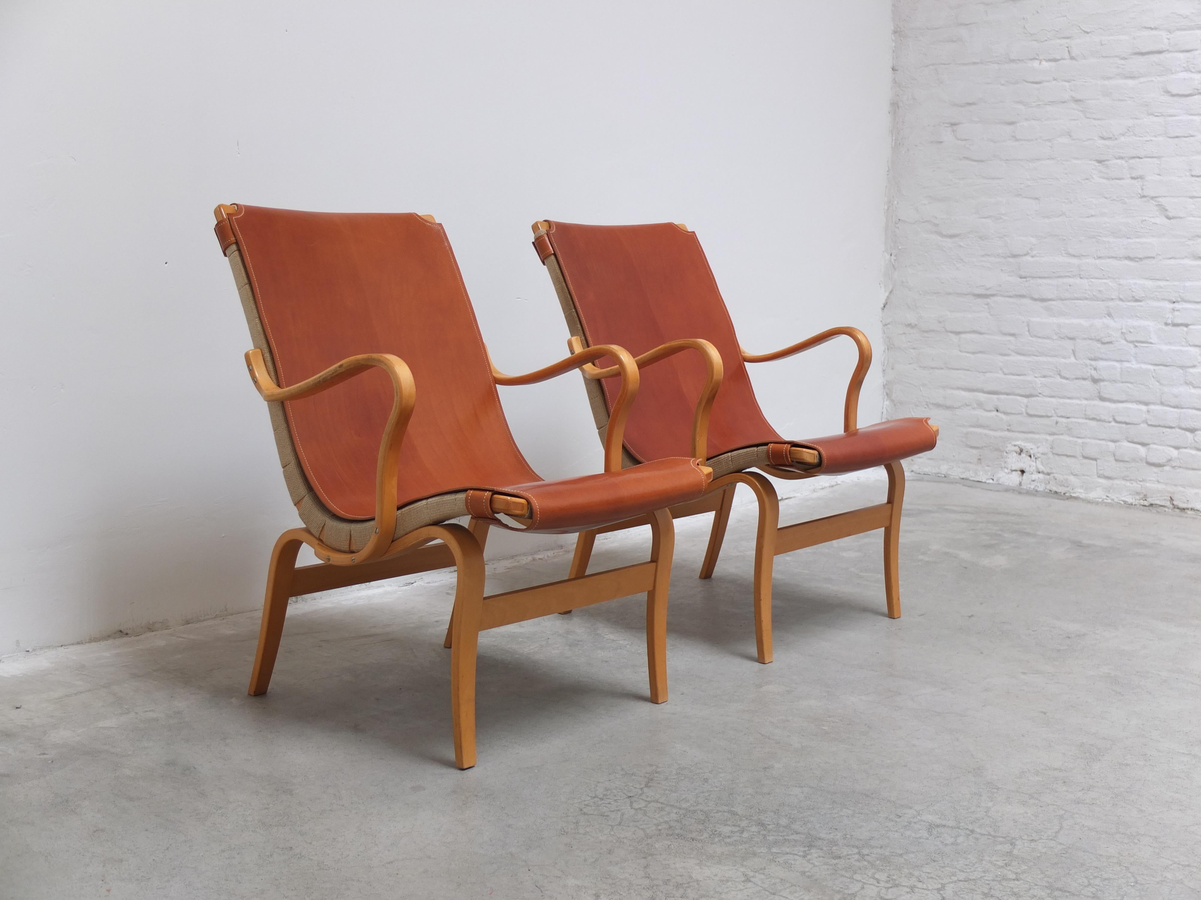 Extremely elegant pair of ‘Eva’ lounge chairs designed by Bruno Mathsson in 1941. This pair is exceptional because they come with newly made high quality covers in cognac saddle leather which gives them a unique and luxury appearance. The chairs are