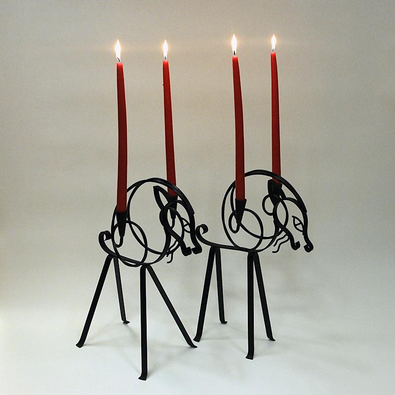 Lovely pair of black forged wired iron candle holders by Gunnar Ander for Ystad Metall 1960s - Sweden. 
These special designed candleholders are shaped as a pair of goats with a candleholder cup on each sides for longer candle sticks. Gives a nice