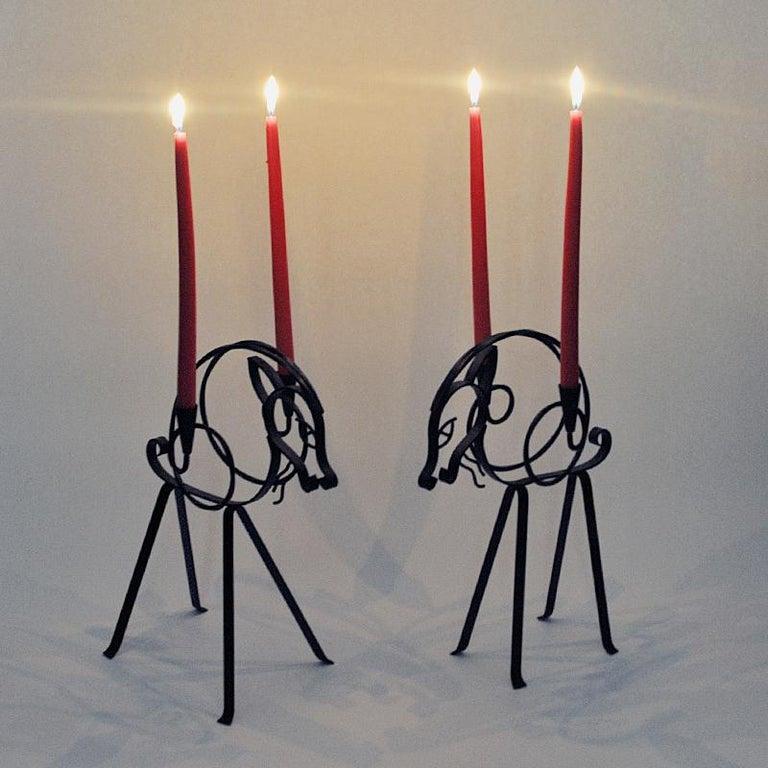 Lovely pair of black forged wired iron candle holders by Gunnar Ander for Ystad Metall 1960s - Sweden. 
These special designed candleholders are shaped as a pair of goats with a candleholder cup on each sides for longer candle sticks. Gives a nice