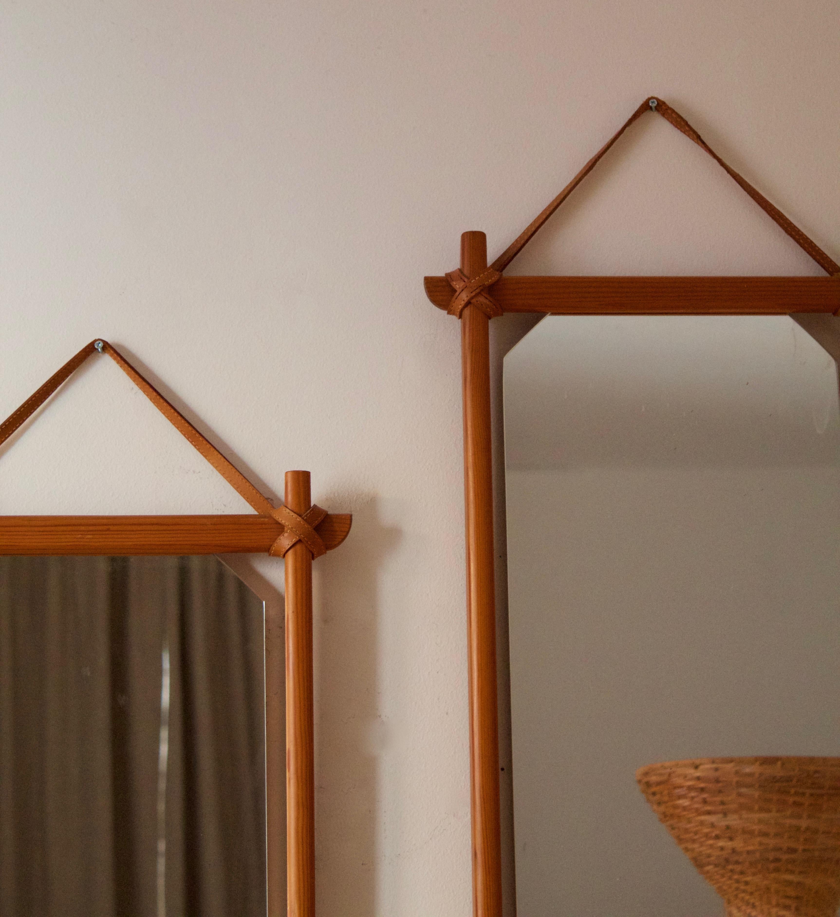 A pair of wall mirrors, designed and produced in Sweden, 1960s-1970s. Features solid pine and natural leather. Custom-cut original glass.