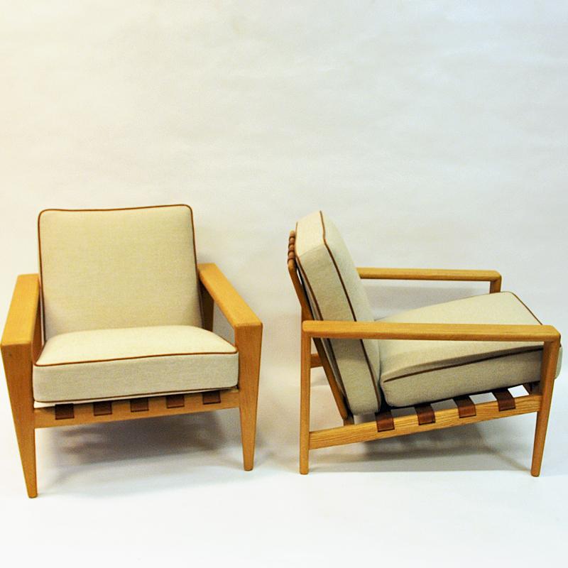 A great pair of oak armchairs model Bodö designed by Svante Skogh 1957 for Säffle Möbelfabrik AB, Sweden. The chairs are made of oak and have solid leather straps on the back and seat. Newly upholstered removable cushions in cream woolfabric