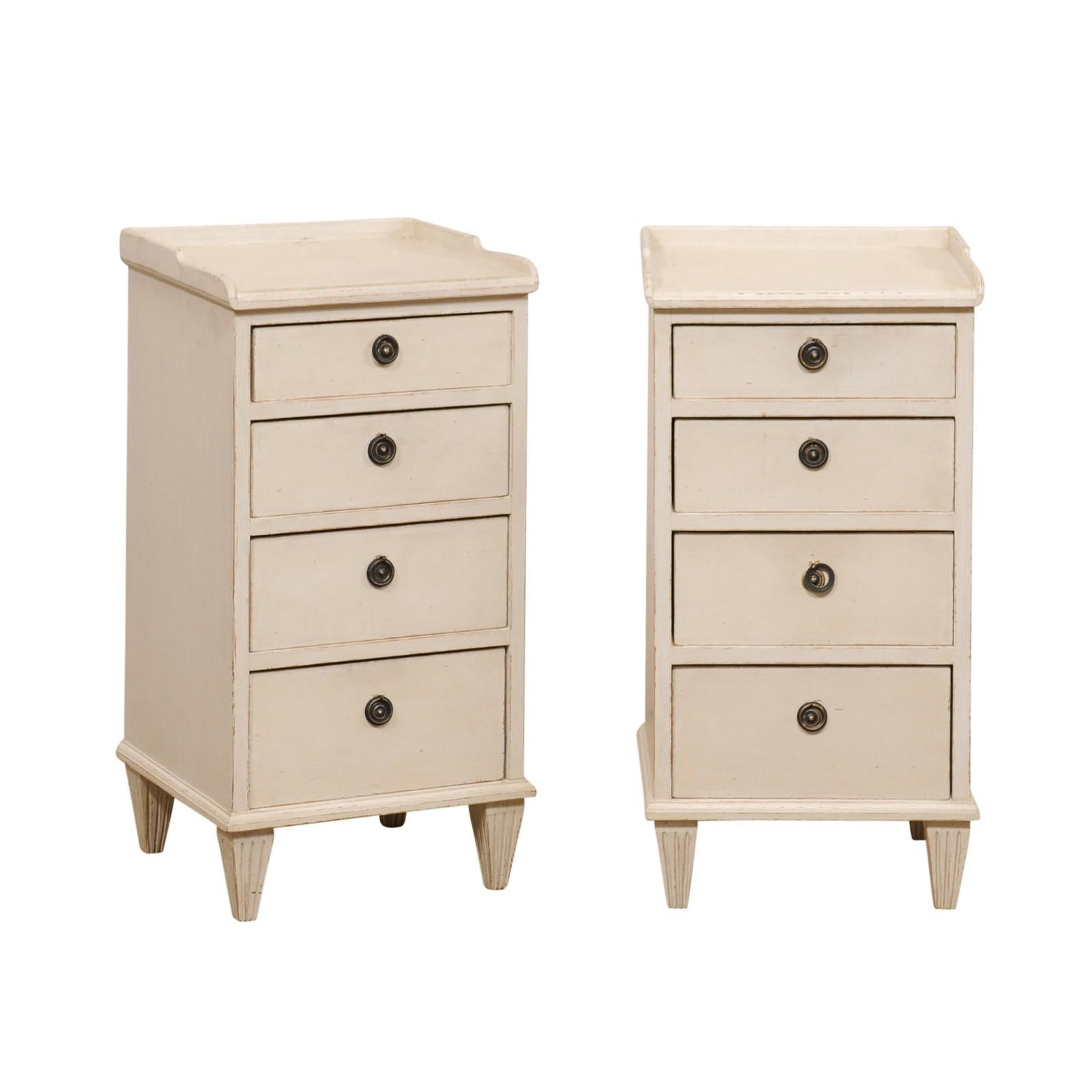 A Swedish pair of painted wood four-drawer side chests, designed in Gustavian style. This vintage pair of petite chests from Sweden each have a raised lip along the top back and sides, atop a cabinet which houses four graduated drawers, and are