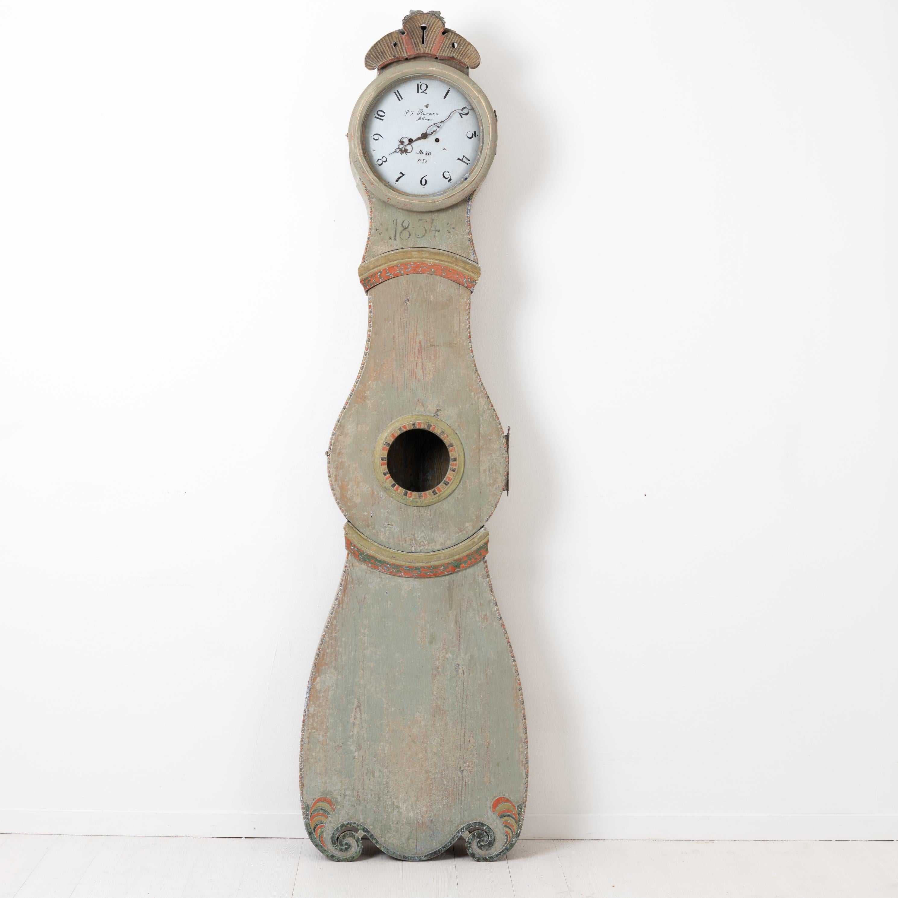 Swedish long case clock made during the early 1800s in Rococo. Made in northern Sweden and dated 1834 with a green toned clock face. The clock is scraped to the original first layer of paint of which the color is a pale green. Healthy and solid