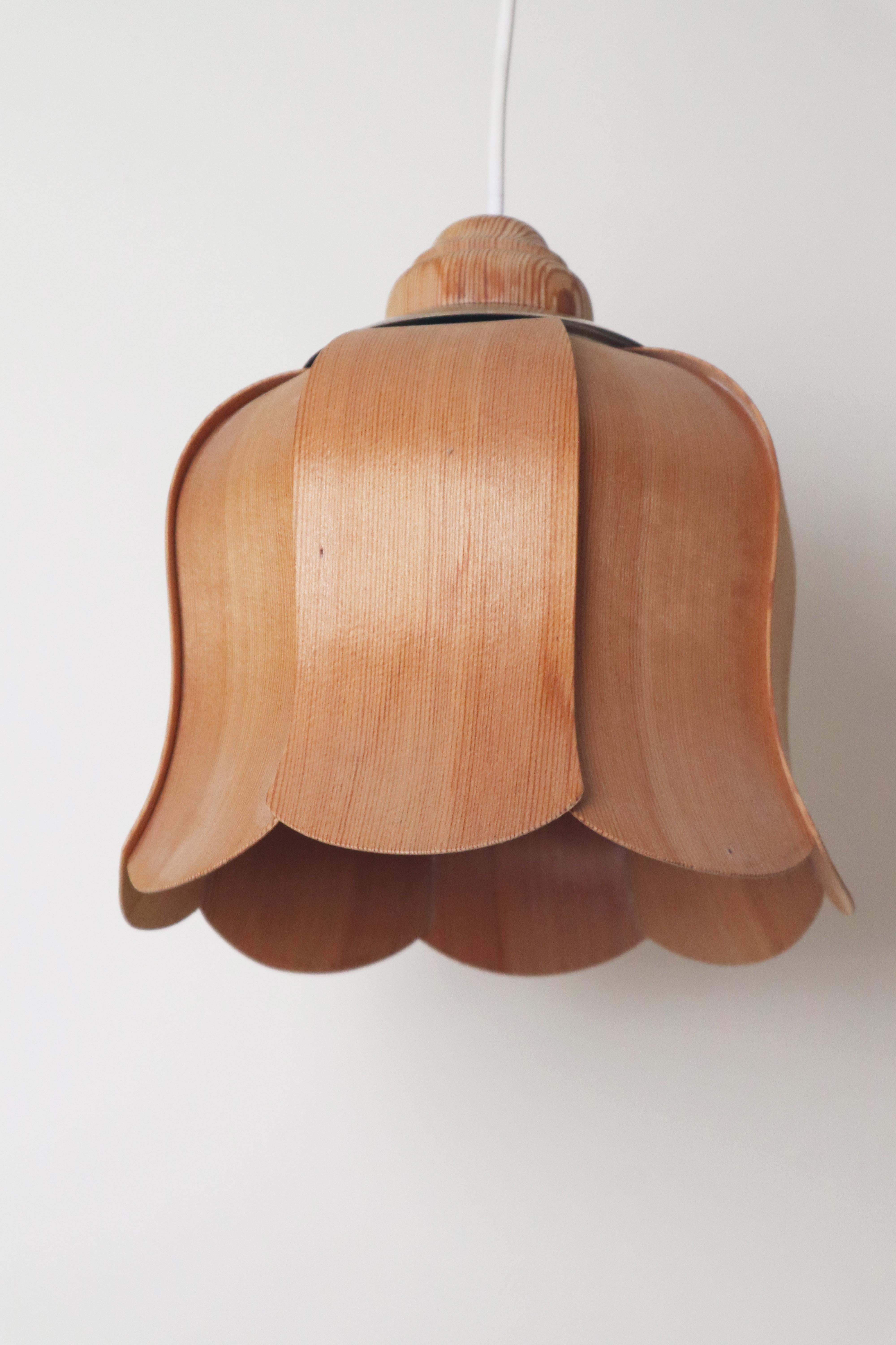 Questa bellissima e rarissima lampada a sospensione a forma di campanula è realizzata in legno di pino. Il design della lampada è molto intricato; il sottile legno di pino piallato è stato accuratamente tagliato a misura e modellato in questa forma