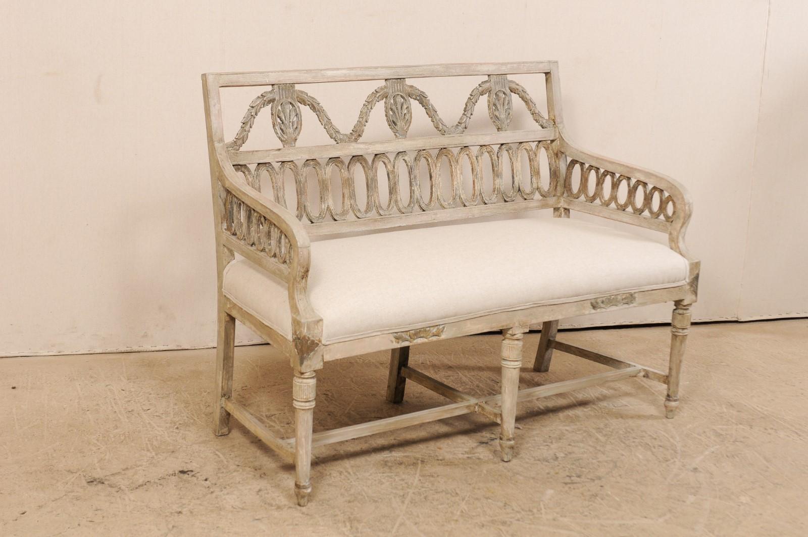 A Swedish period late Gustavian sofa bench with upholstered seat form the early 19th century. This antique sofa bench from Sweden has beautiful carved pierced splat backs in an oval-ring and garland motif. The sofa has a flat top rail along back,