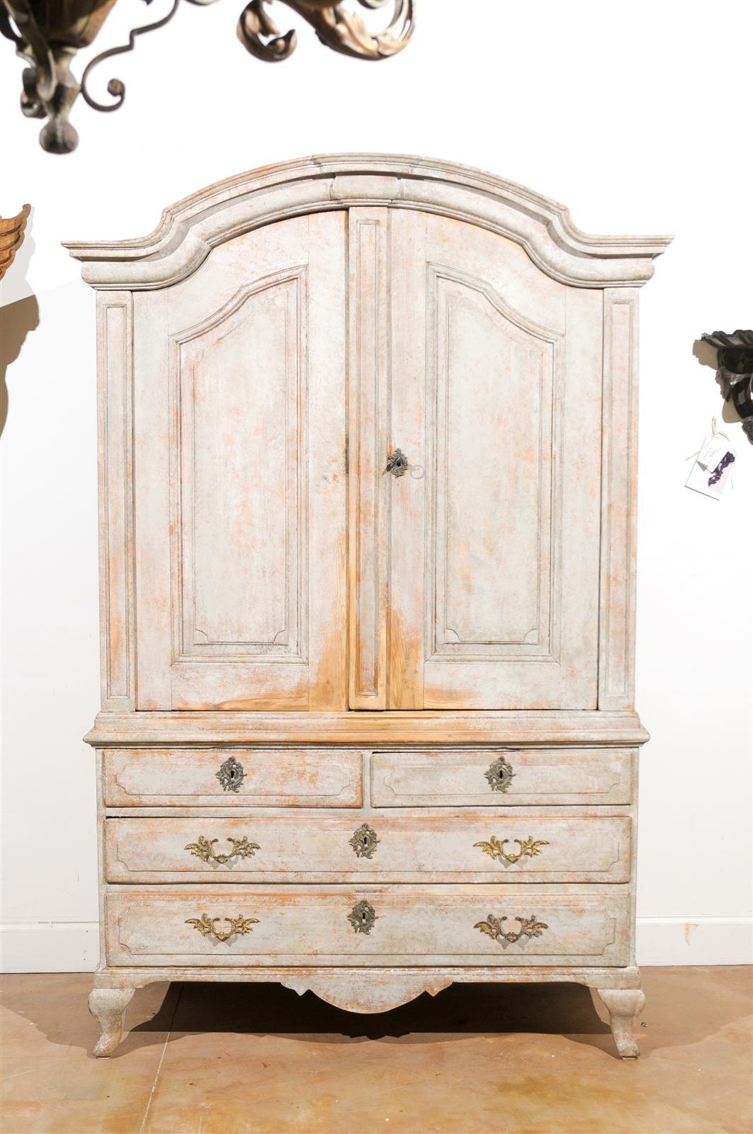 A Swedish Rococo period painted wood cabinet with original paint, bonnet pediment and double doors over four drawers from the mid-18th century. This Swedish painted cabinet features a bonnet type pediment, typical of the Rococo era, surmounting a