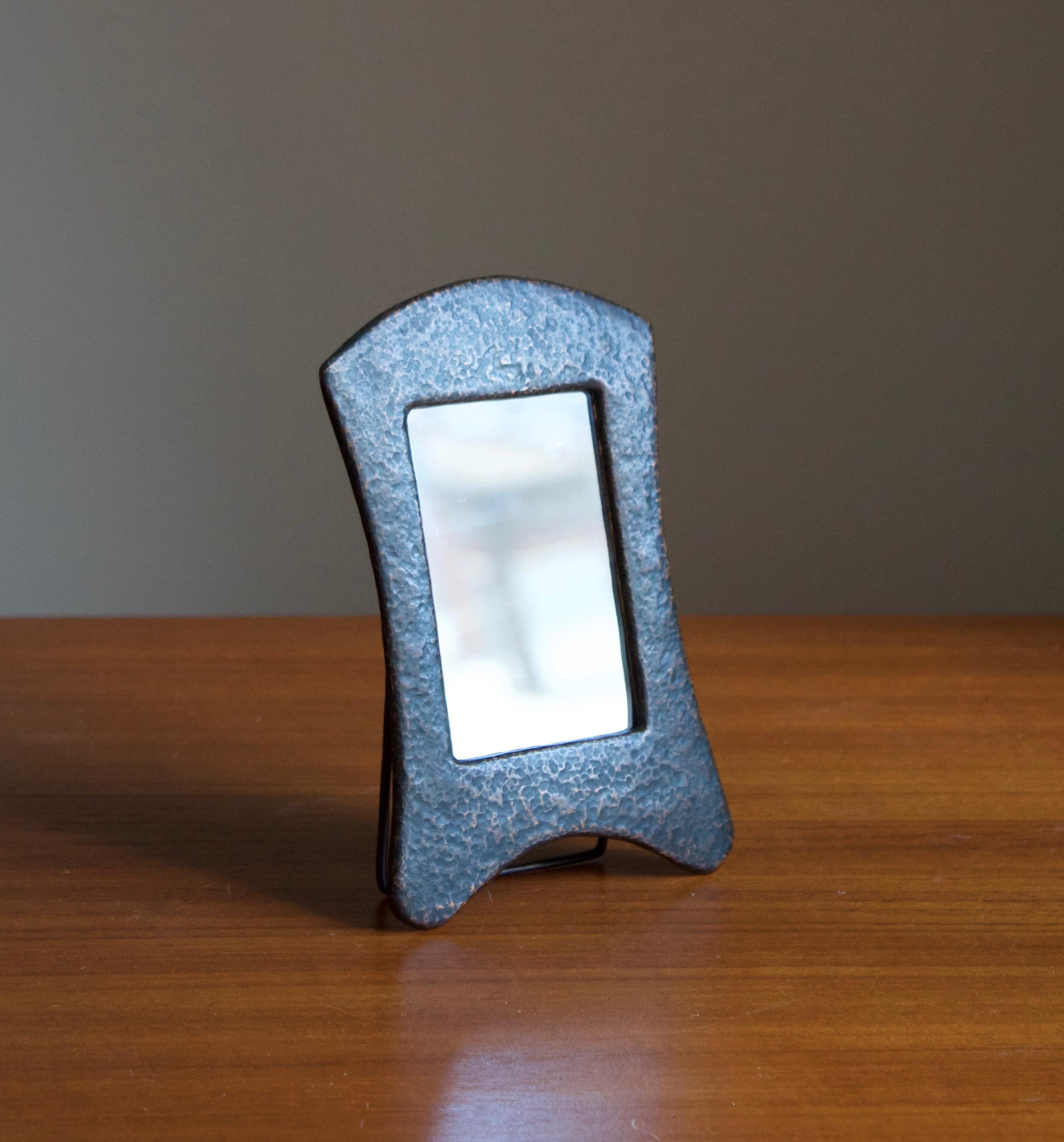 A petit table mirror. Designed and produced in Sweden, 1930s. In hammered copper.