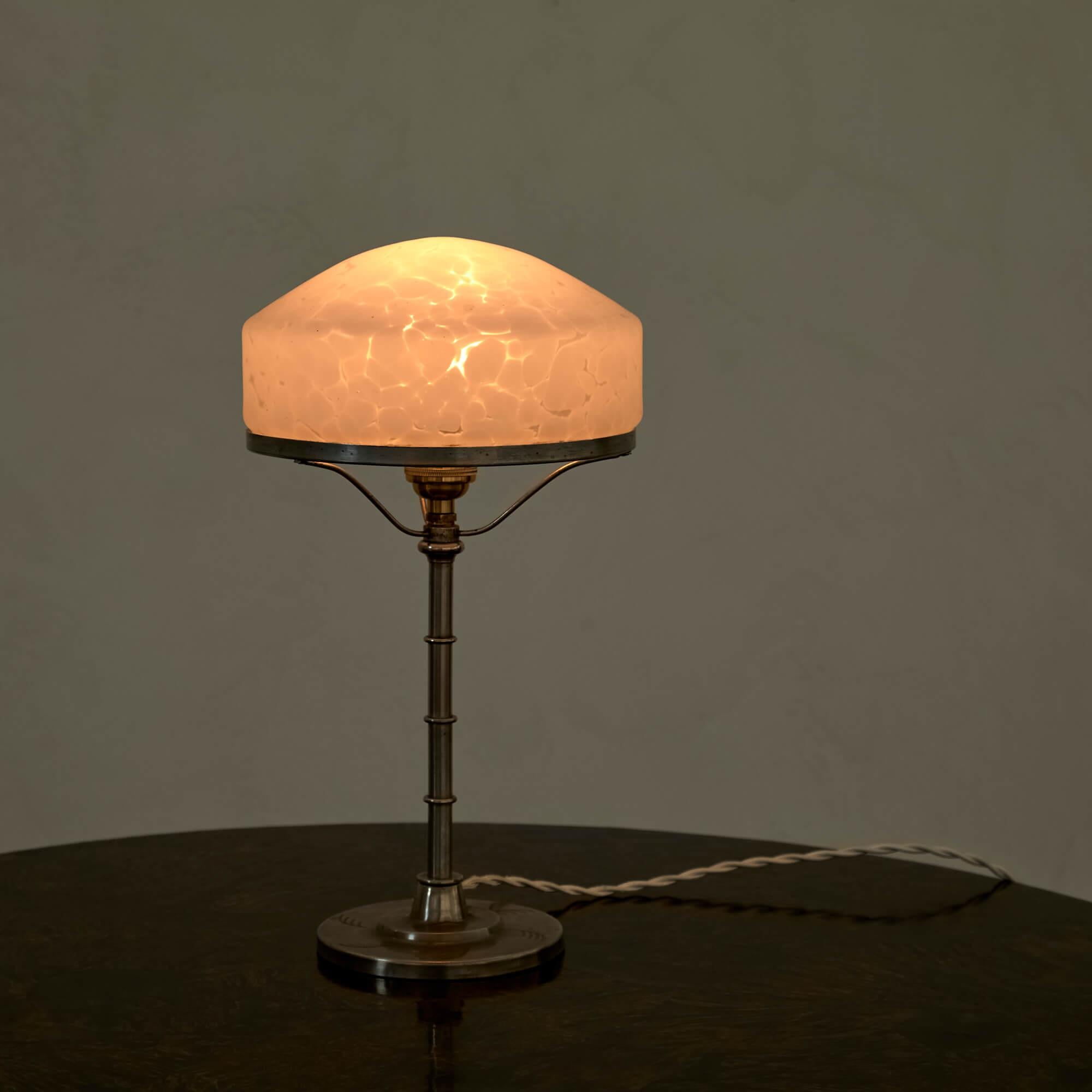 This elegant table lamp emits a warm glow from its mottled white glass shade. With a spare herbaceous design etched on the pewter base.

Rewired for the U.S. with a twisted cloth cord.