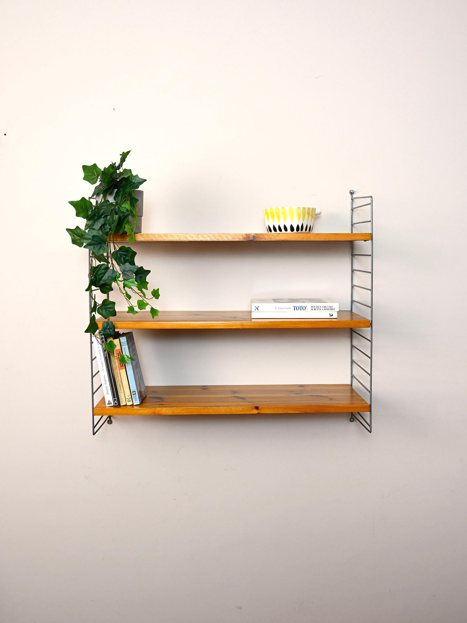 Scandinavian 1960s wall-mounted bookcase.

This simple shelving system consists of a metal side frame on which three pine shelves rest.
Simple and functional it can be hung in different rooms of the house.

Good condition. It has been restored with