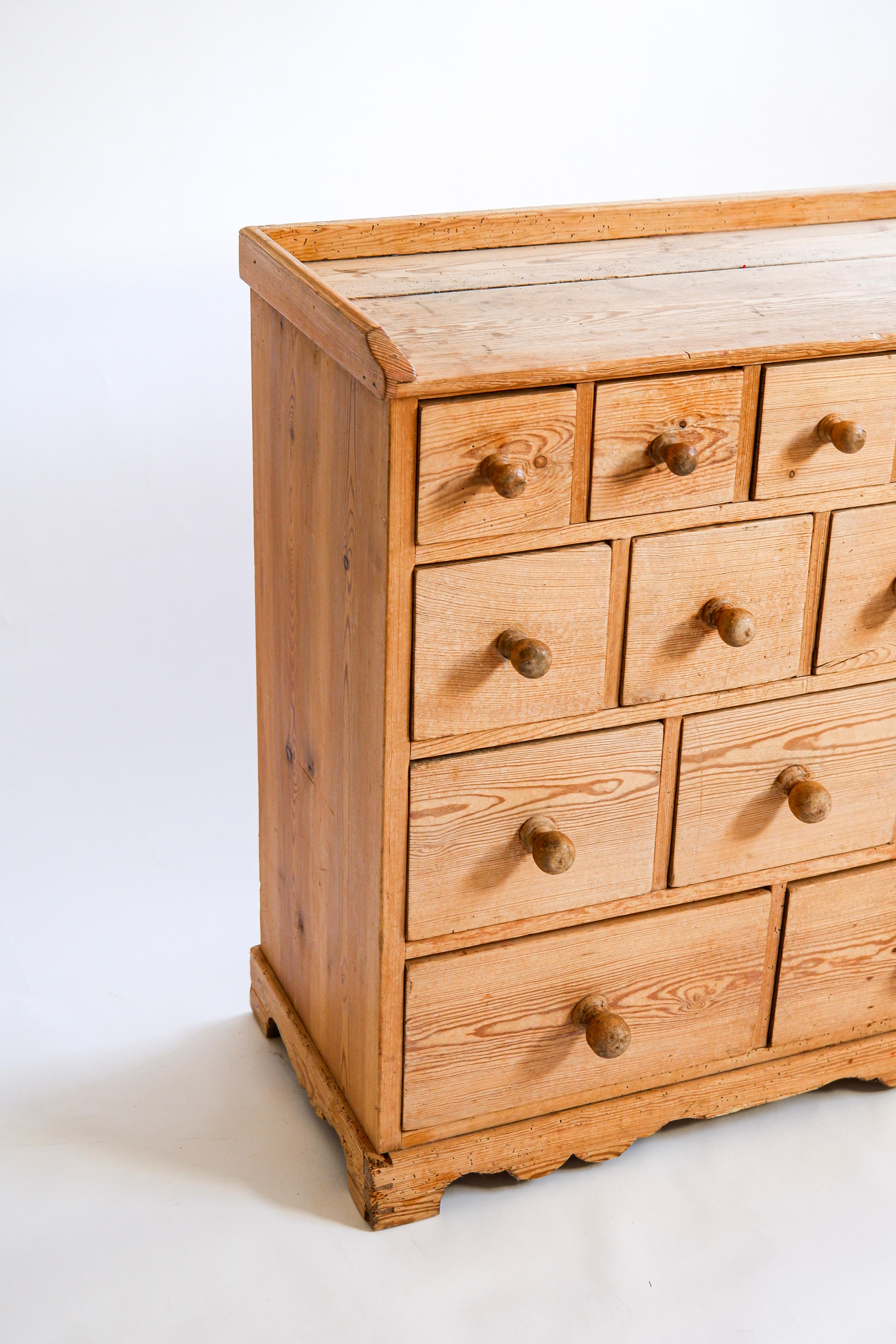 Armadio svedese con 14 cassetti in pino massiccio. Tipica arte popolare realizzata a mano, in buone condizioni originali. Questo mobile può essere collegato allo stile di Axel Einar Hjorth in Svezia nel secondo secolo.
