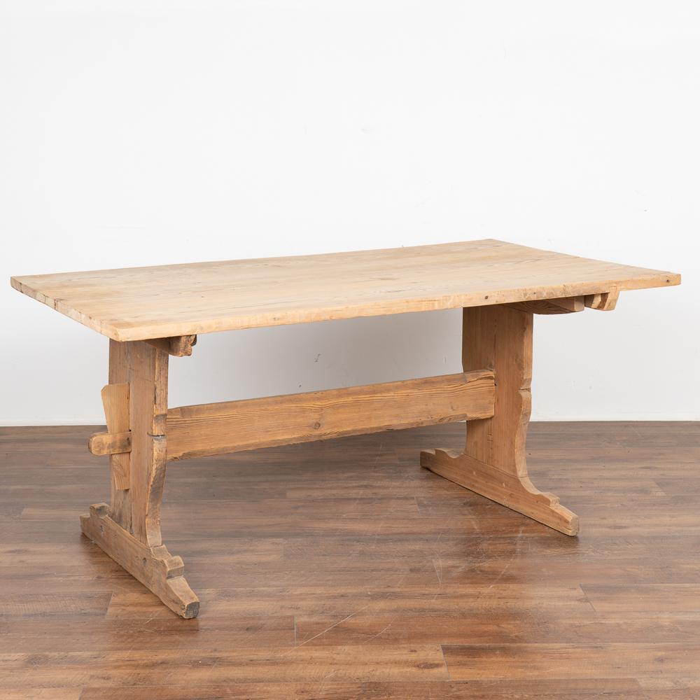 This farmhouse kitchen or dining table has European country charm thanks to wide leg trestle base.
The natural pine has been distressed through generations of use, adding depth to the character of the table. The many scratches, dings, stains and age