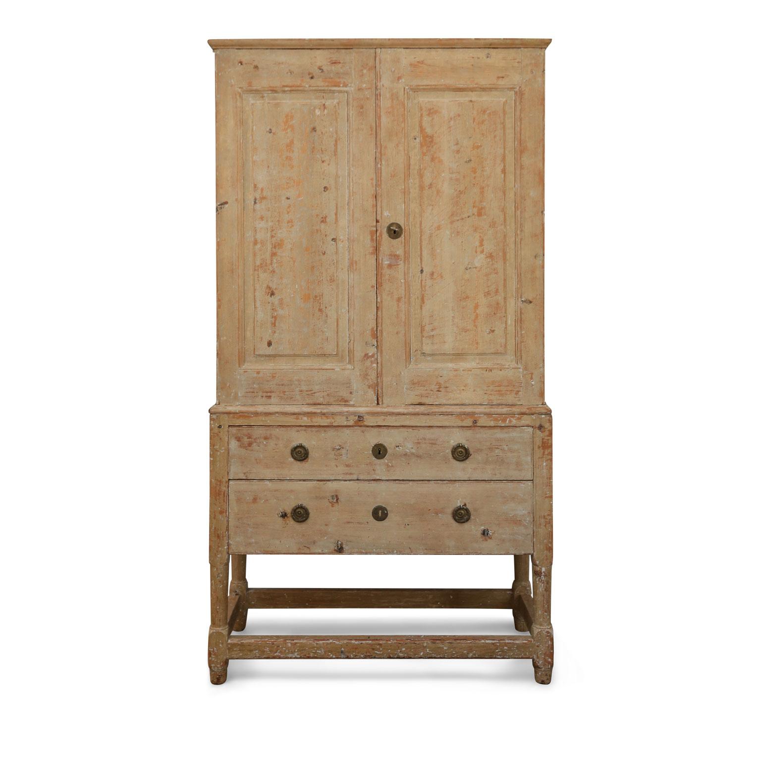 Swedish pine tall cabinet: early 19th century transitional hand-carved cabinet-on-chest raised on turned legs. Upper two-door cabinet holds multiple open compartments for storage. Lower chest contains two full-width drawers.