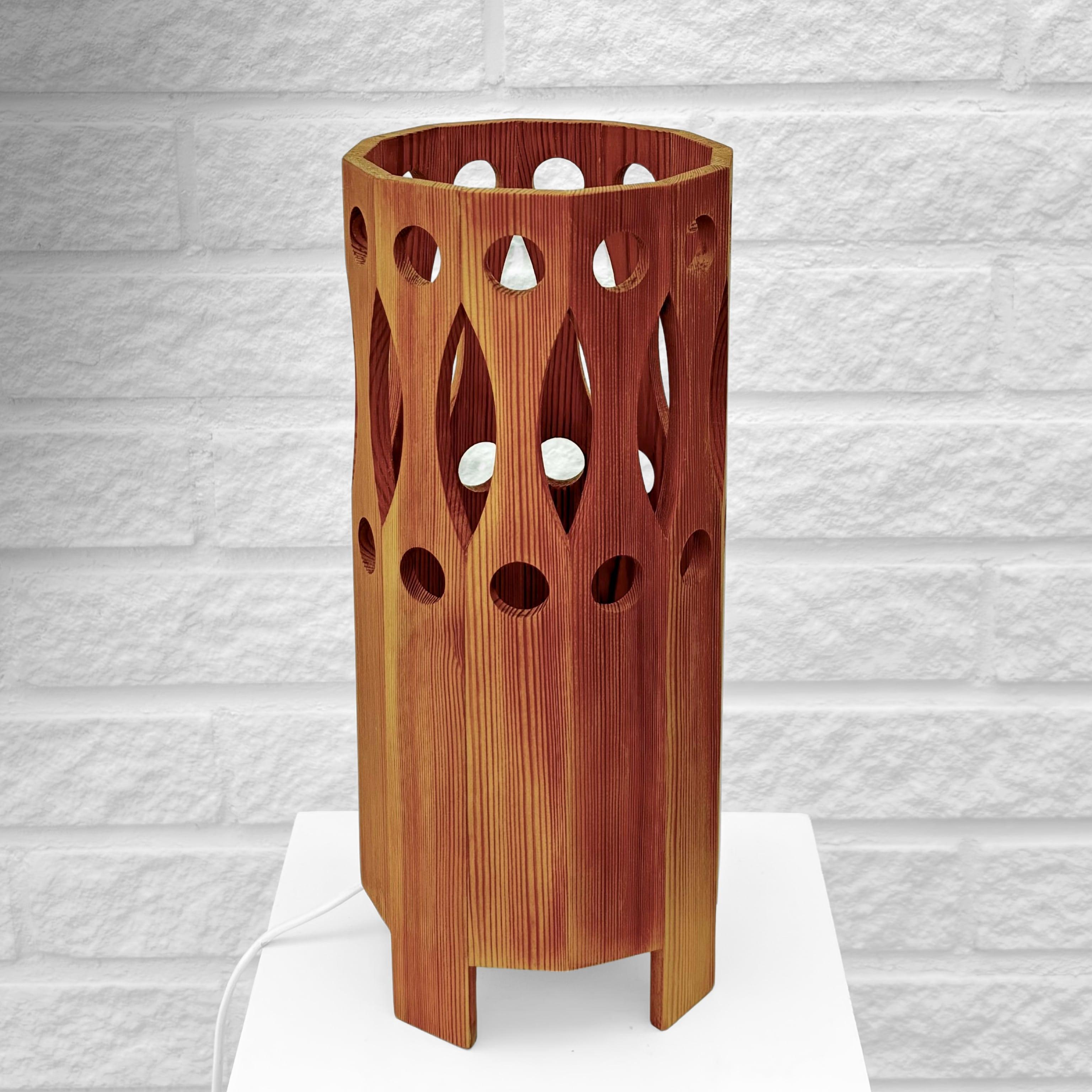A minimalist pinewood table lamp designed in the 1970s by L.O. Nilsson for the small Swedish manufacturer Nordisk Present in Östersund. It features a cylindrical body crafted from solid pine with a geometric pattern of circles and ellipses. The