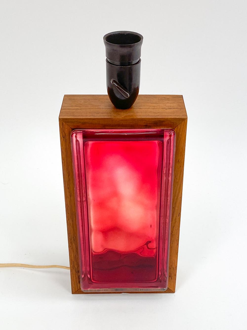 Step into the radiant world of 1960's Swedish design with this dazzling table lamp, in which a fiery red glass block forms an unexpected match with opulent rosewood. An artifact of an age when design broke barriers, this lamp encapsulates the daring