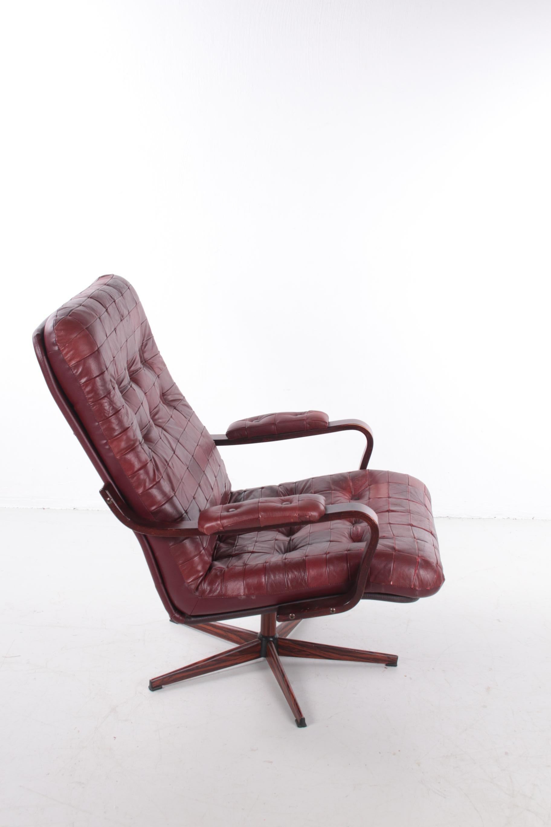 A beautiful vintage armchair in the style of De Sede. This chair was made in Sweden around the 1970s.

The chair is upholstered in a collection of deep red leather patches. The deep red color, the checkered pattern and the grain of the wood give the