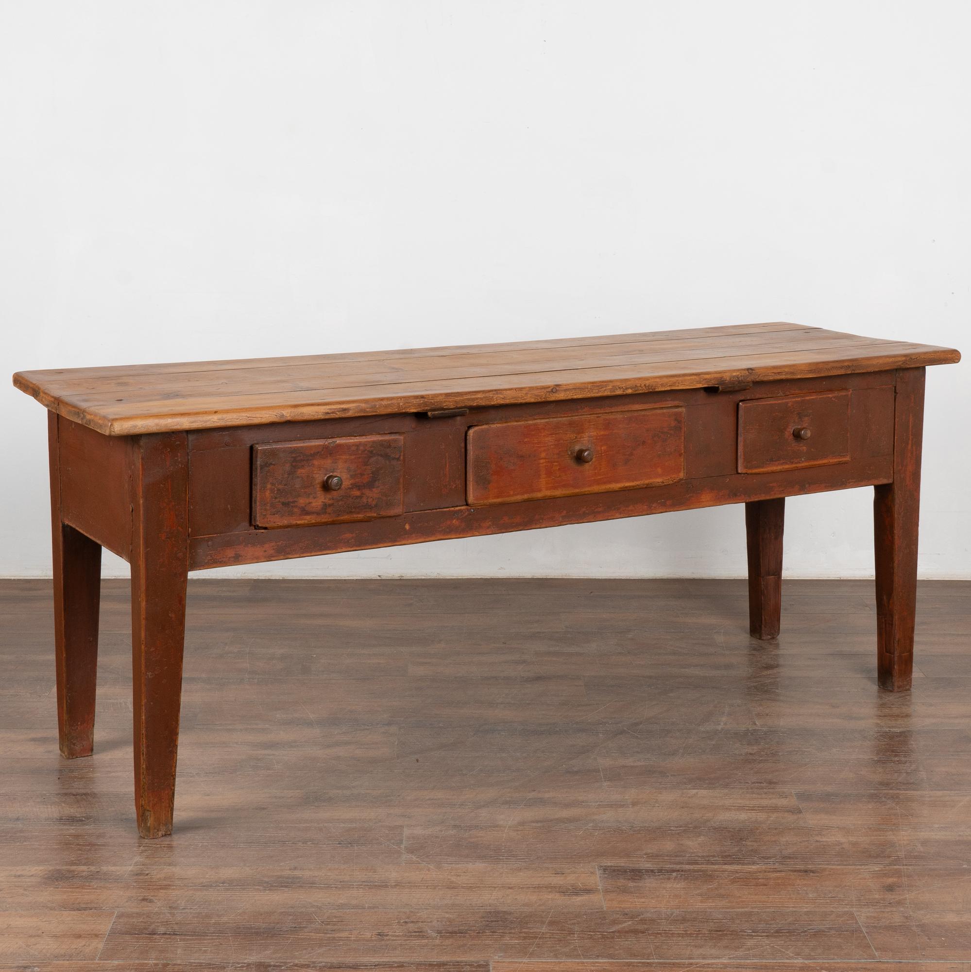 The perfect aged patina in the brick red painted finish is complimented by a contrasting natural pine plank top in this delightful farm table from Sweden which will serve well as a console table.
Top reveals gouges, scratches, stains and age related