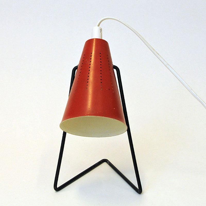 Lovely red enameled metal table/desk lamp designed in 1955 by Svend Aage Holm Sørensen for Asea, Sweden. These cone shaped rare lamps can be adjusted in different directions, even straight up. Black metal L-shaped legs.
Unique design.
The metal