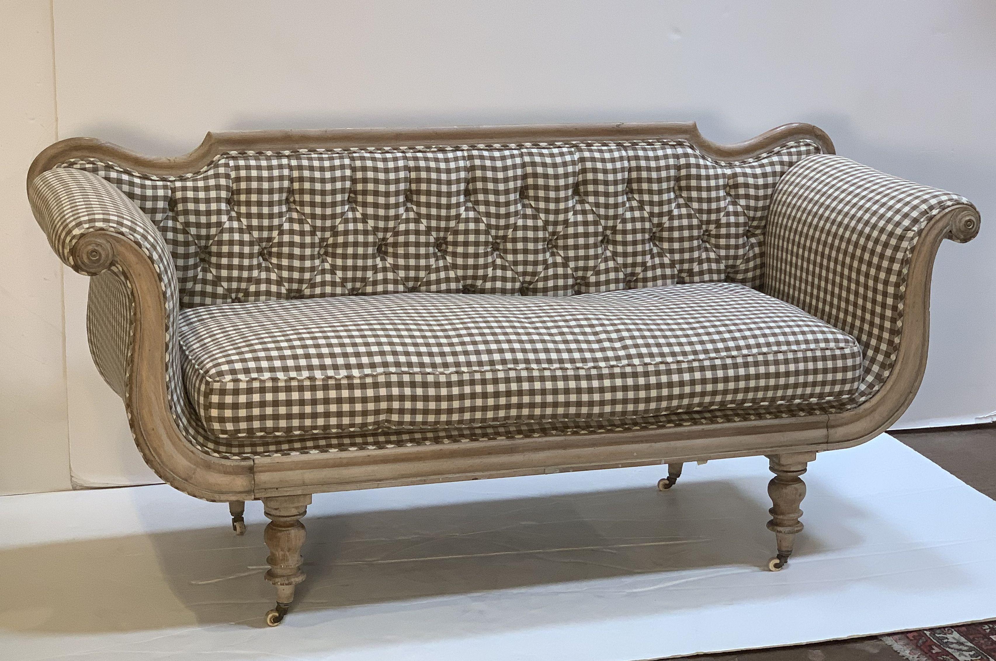 A fine, comfortable Swedish sofa from the Regency Period, featuring a serpentine lyre-shaped profile with newly-upholstered button-tufted back, scrolling arms, a fitted seat cushion, and resting on turned legs with casters.

  