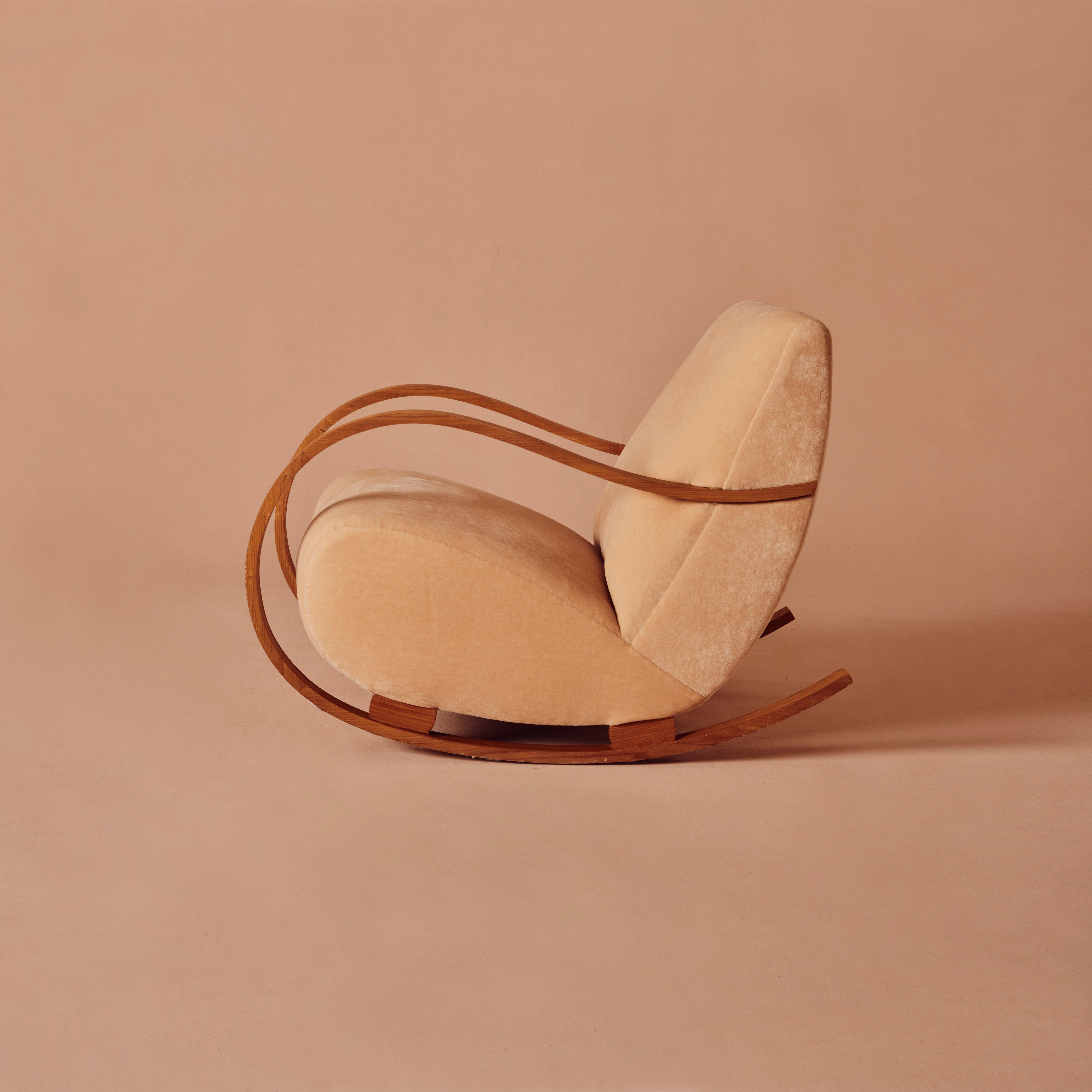 Questa sedia a dondolo svedese Art Deco è stata prodotta negli anni '40 ed è stata completamente restaurata e rivestita in velluto rosa. Gli ampi bracci del design sono parte integrante della struttura e dell'estetica del pezzo. Di grande impatto