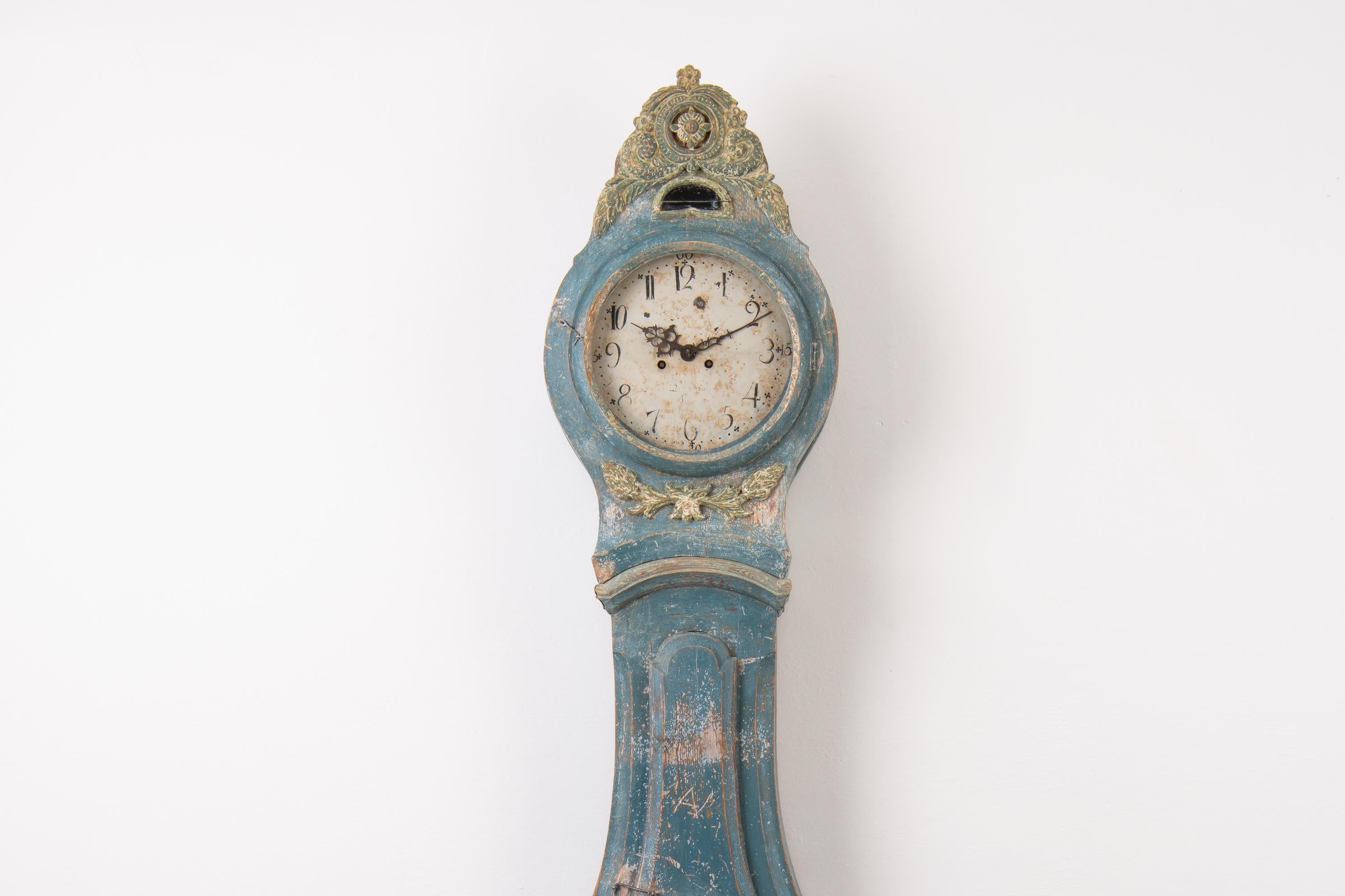 Swedish long case clock from the transitional period between Rococo and Neoclassicism. The clock has influences from both periods. The blue paint is the original first layer and it has naturally patinated over the years. The paint is distressed in