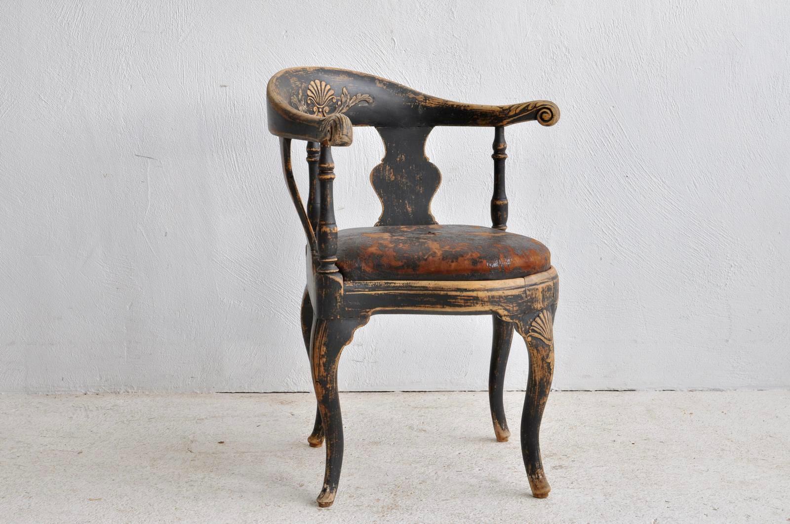 A period Swedish Rococo corner chair, black painted and with an old leather seat.