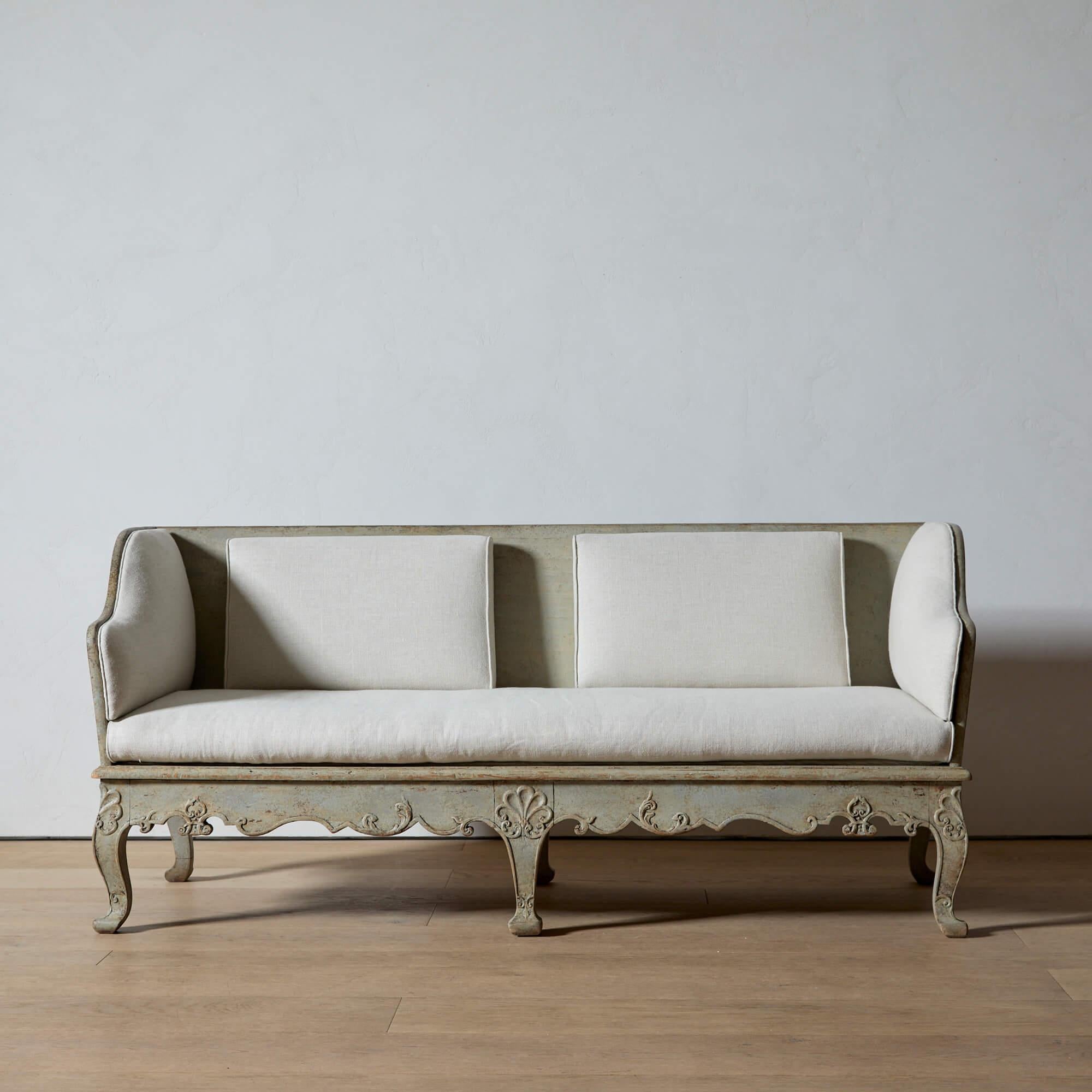 The Swedish “trågsoffa” is a traditional wooden sofa of the Rococo and Gustavian periods, usually made of fir, and decoratively carved.

This example is beautifully ornamented with scrolling, foliate carvings along the apron and six legs. The wood