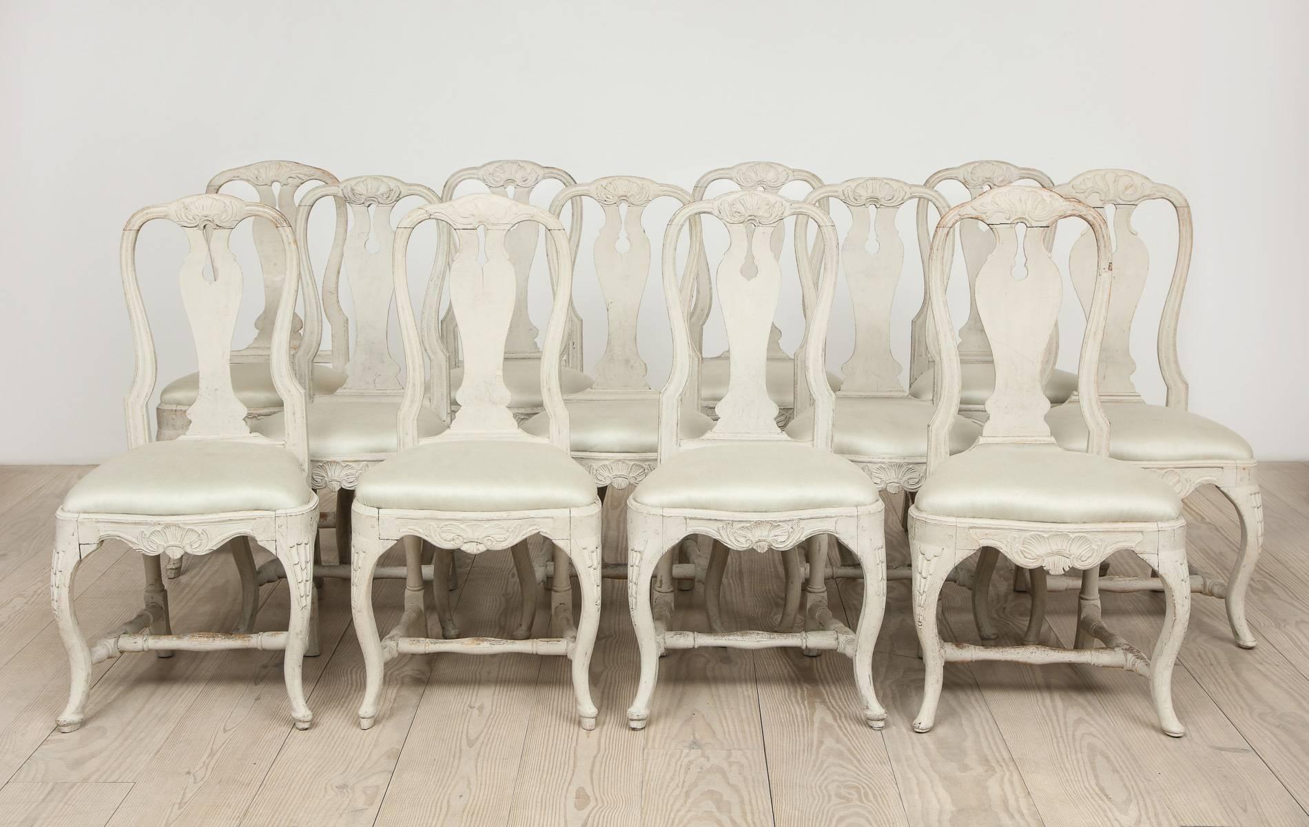 Swedish Rococo dining chairs, set of 12, circa 1765, Origin: Stockholm, Sweden

Measures: Seat height 19-3/4 inches

Cabriole legs with wide knee and paw feet, carved with rocaille, leaves, shells. Back splat with an open key hole. Seats