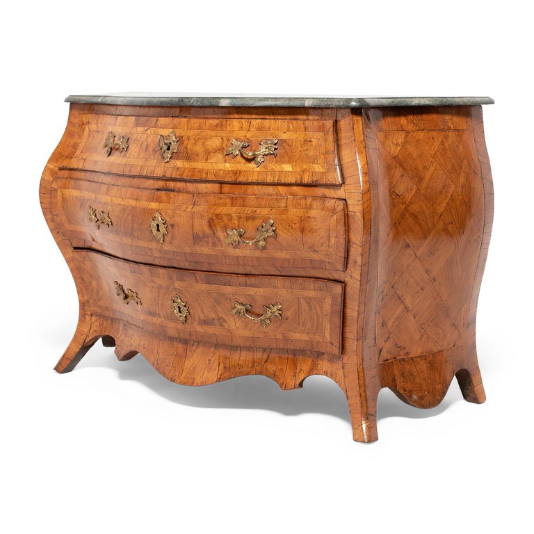 This magnificent three-drawer bombe commode dates to the mid-18th century and exemplifies the Swedish Rococo furniture style. The commode has a pleasing curvilinear shape, a sinuous line drawn by the high knees, flared legs, and outward swell of its