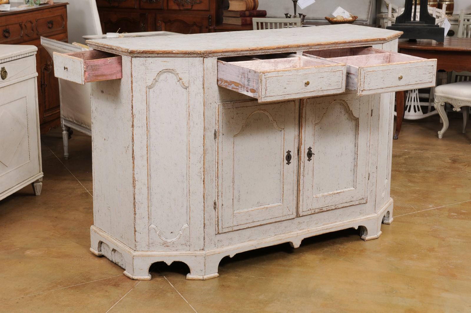 A Swedish Rococo period 18th century painted wood buffet from Värmland, with canted sides, four drawers and two doors. Created in the west-central province of Värmland during the 18th century, this painted buffet features a polygonal top sitting