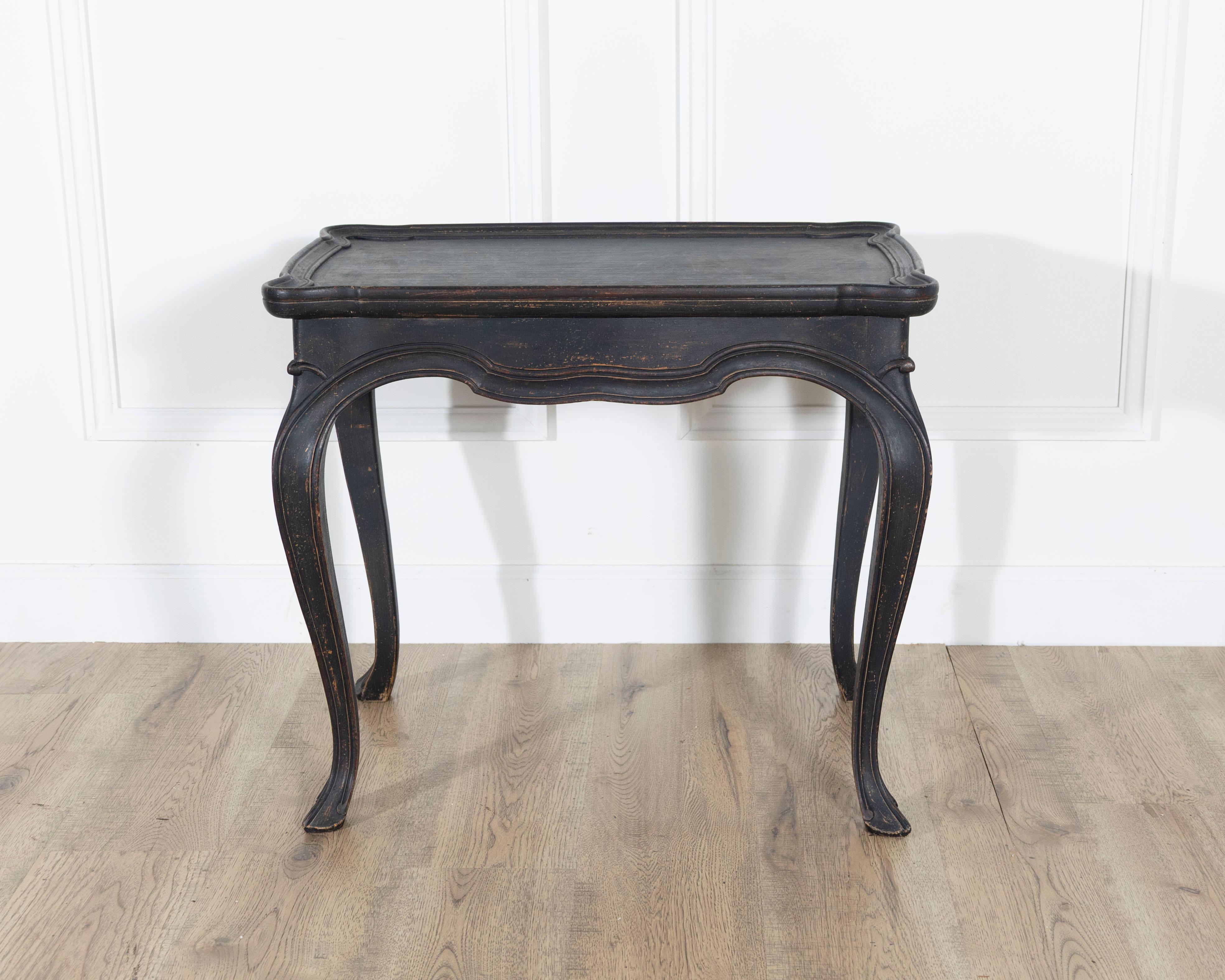 A graceful Swedish coffee table in the Rococo style, dating to circa 1910, combining elegant curves with a timeless dark patina. The table’s cabriole legs flow seamlessly into a delicately scalloped apron, creating a soft and fluid silhouette