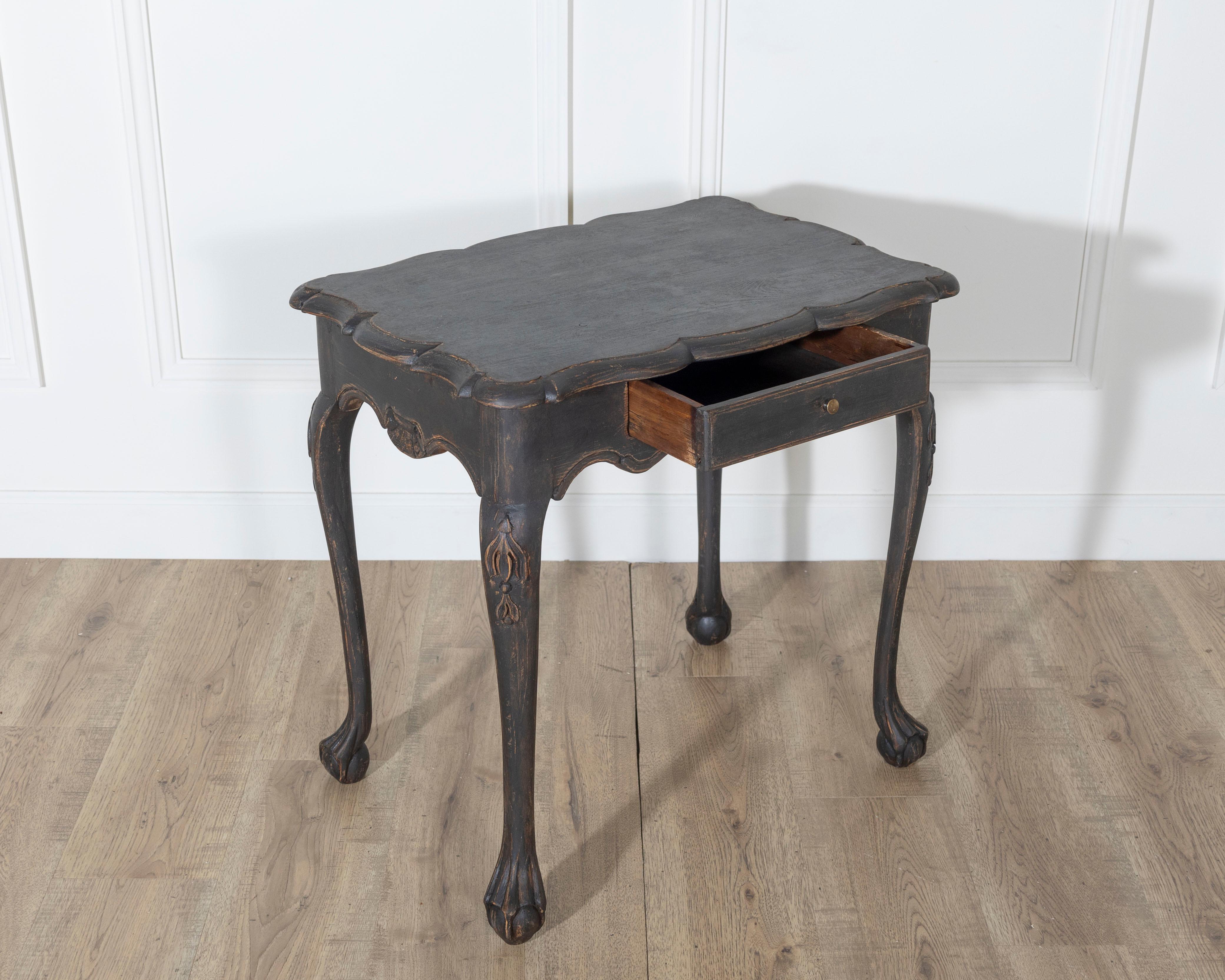 An elegant Swedish Rococo table circa 1780, showcasing the sinuous charm and refined craftsmanship of the period. This sculptural piece features a shaped top with serpentine edges, gracefully echoing the movement of the carved apron and cabriole