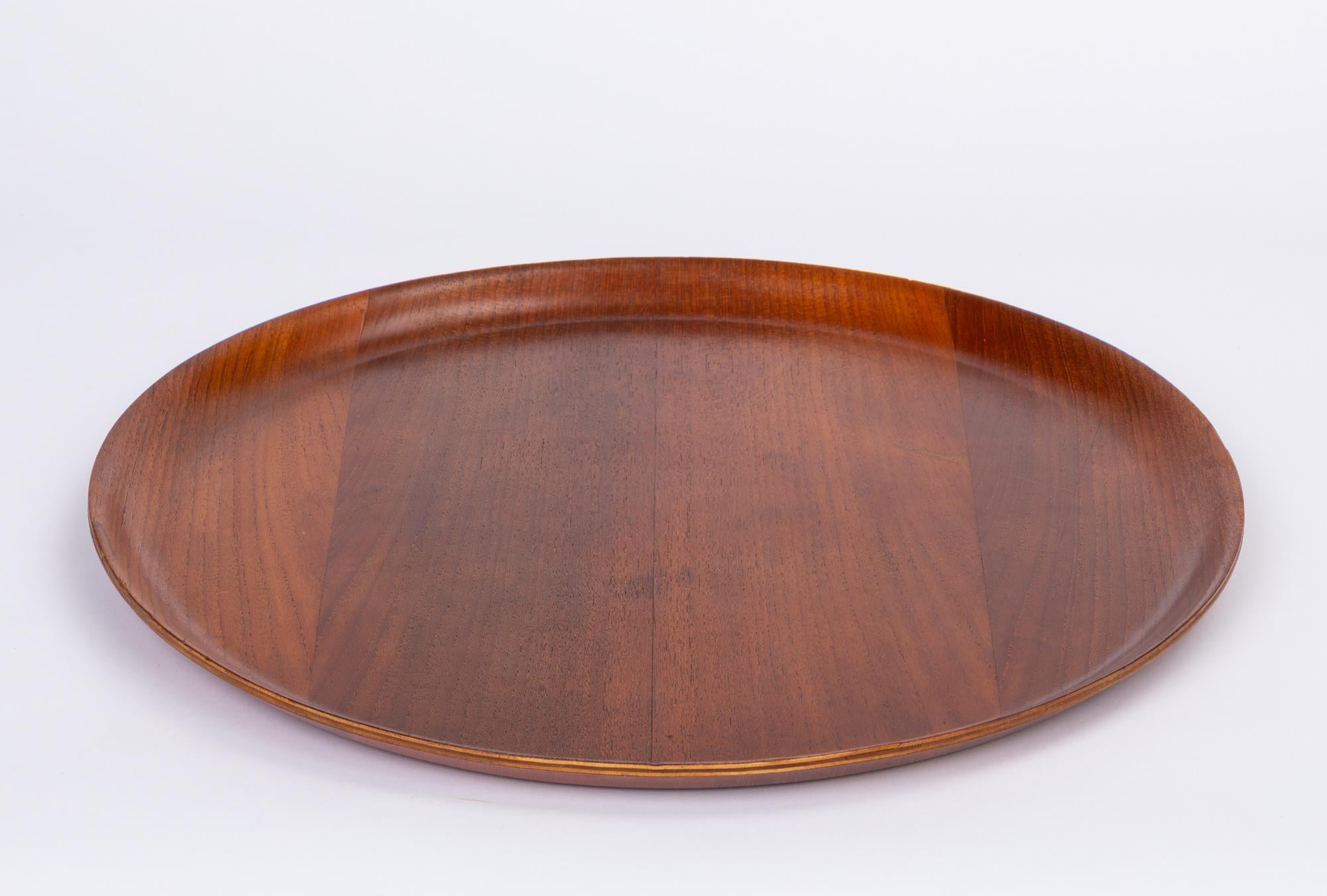 Round teak serving tray from Sweden. The tray features curved raised edges and beautiful grain that is more apparent with the hand applied oil finish.

Marked on underside [Made in Sweden]

Dimensions: 18” diameter x 1’ height.

Condition: