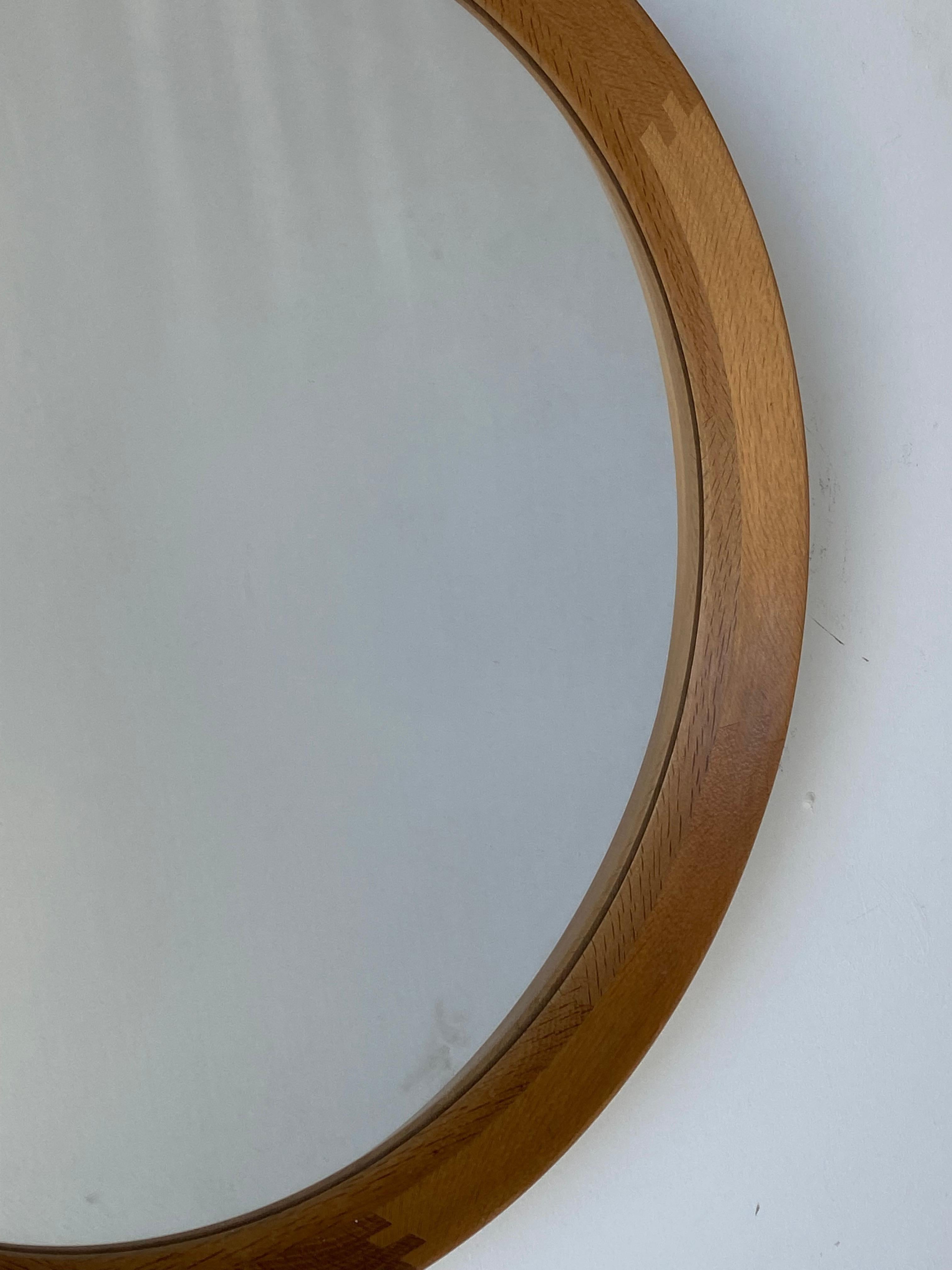 A stained oak mirror, glass with a finely sculpted solid oak frame wrapping the glass in a round form. 

Other designers of the period include Hans Wegner, Josef Frank, Finn Juhl, George Nakashima and Arne Jacobsen.
