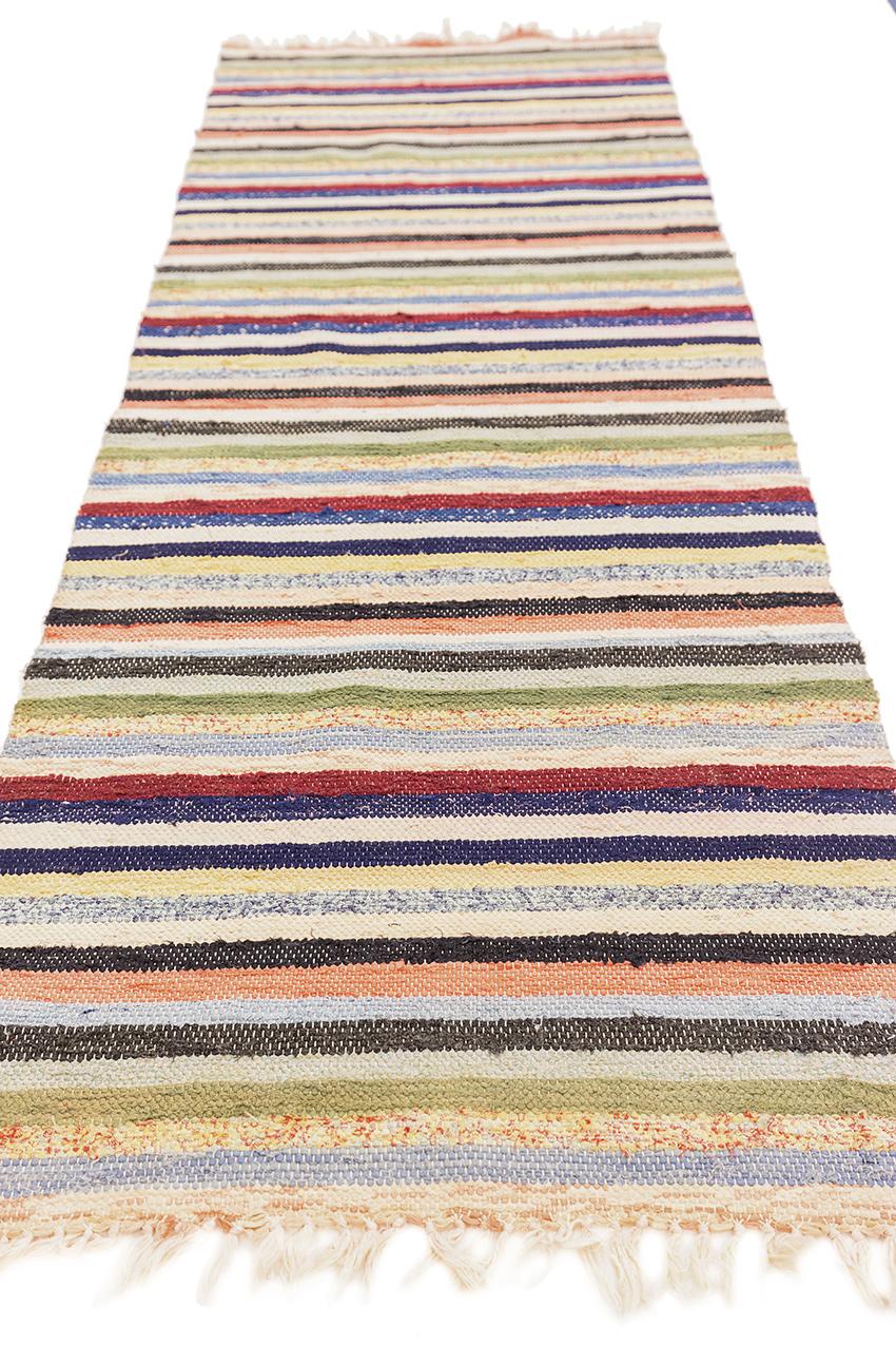 Questo tappeto svedese, che misura 66 x 179 cm, è una sinfonia visiva di colori, sapientemente intrecciati per dare un tocco di vivace eleganza a qualsiasi spazio. Le strisce di beige, blu, marina, bianco, verde e azzurro si fondono armoniosamente,