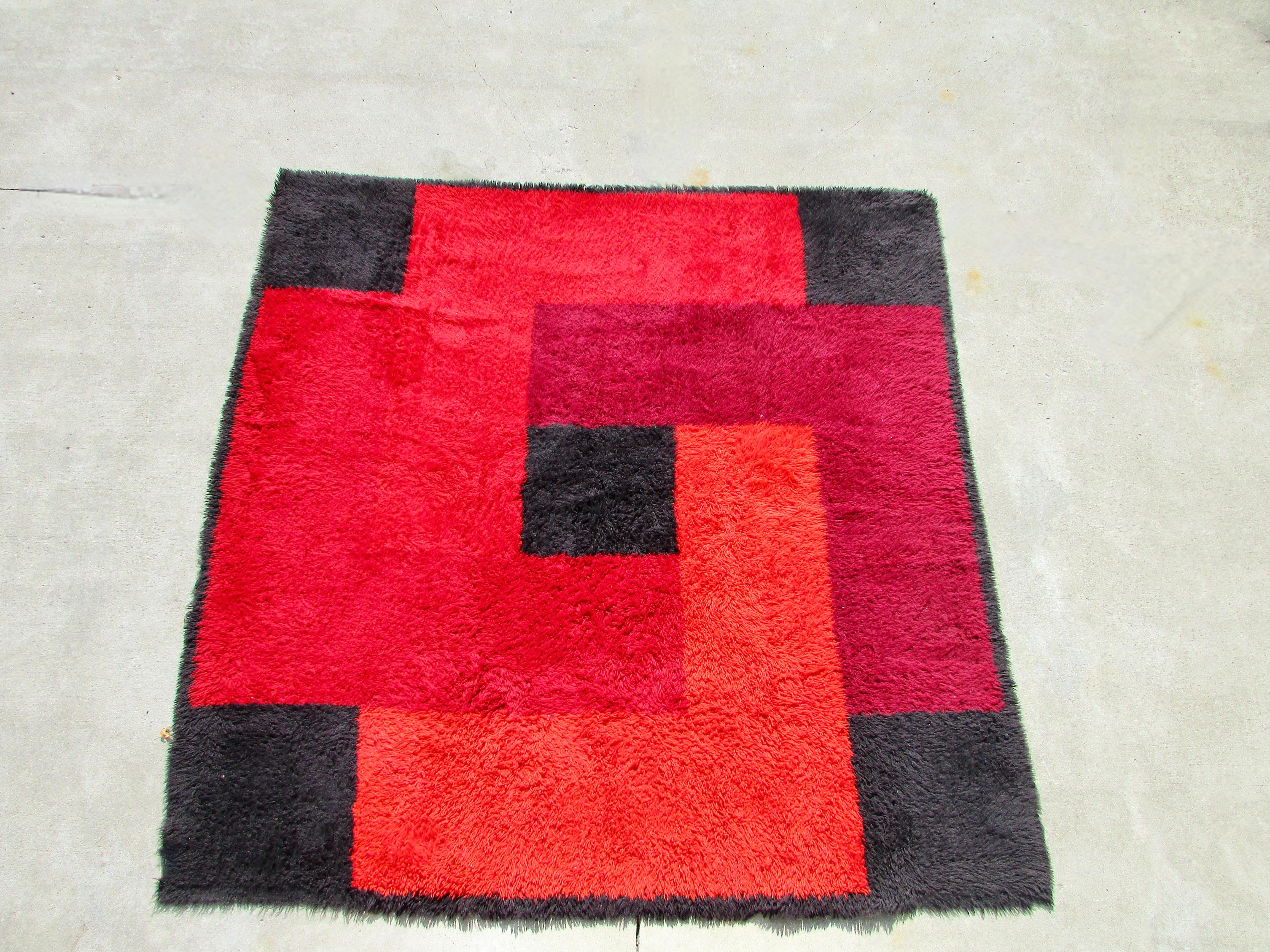 Deep dense 100% wool shag pile square rya rug produced in Denmark circa 1965 by Dania Taepper in a geometric collage of contrasting reds and black. Measures: 90